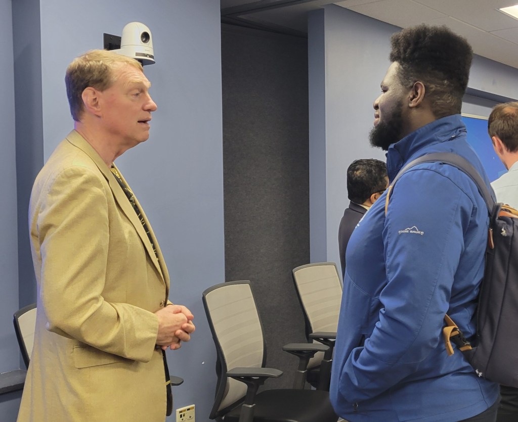 Two men are standing facing each other as they engage in conversation.