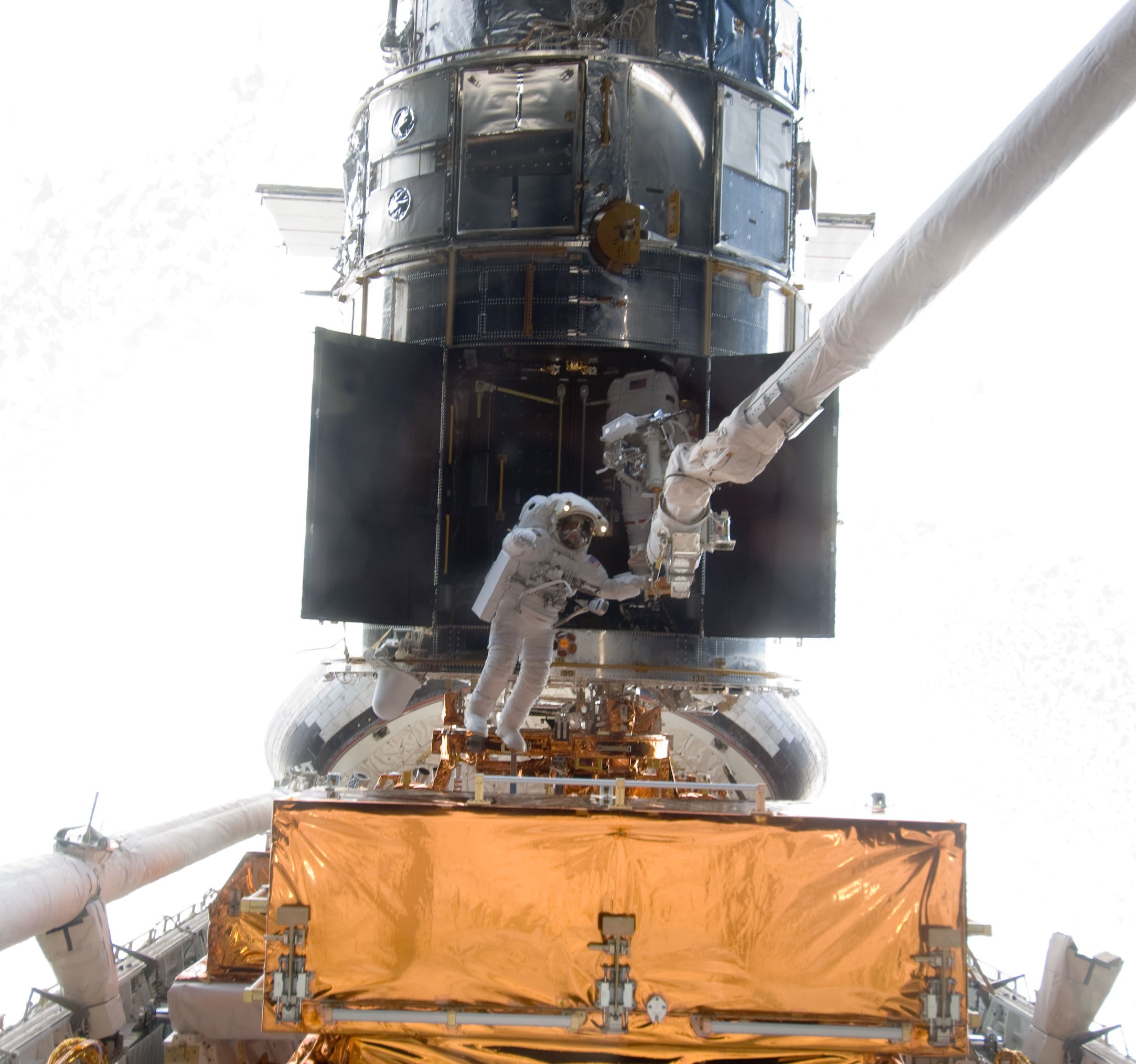 Andrew J. Feustel, left, and John M. Grunsfeld remove the Corrective Optics Space Telescope Axial Replacement (COSTAR) instrument