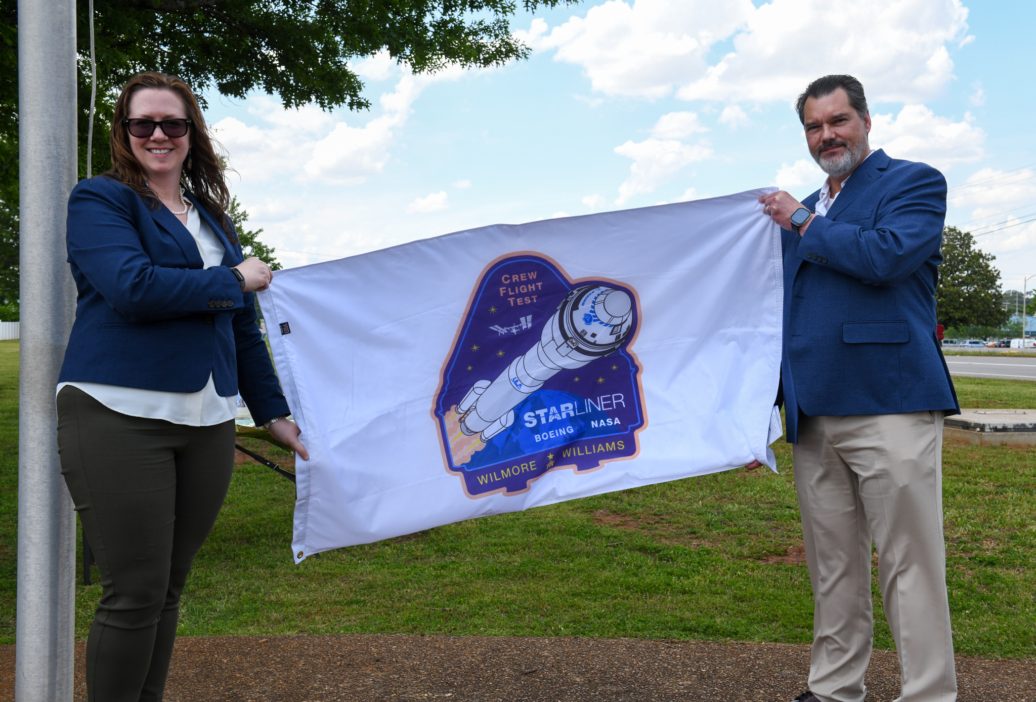 McCollum and Norris display the Starliner flag before it was raised outside the Huntsville Operations Support Center.