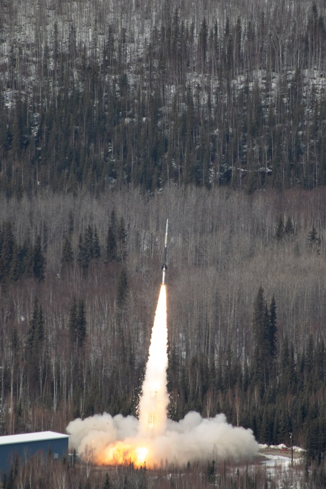 A HI-C launches with trees in the background.
