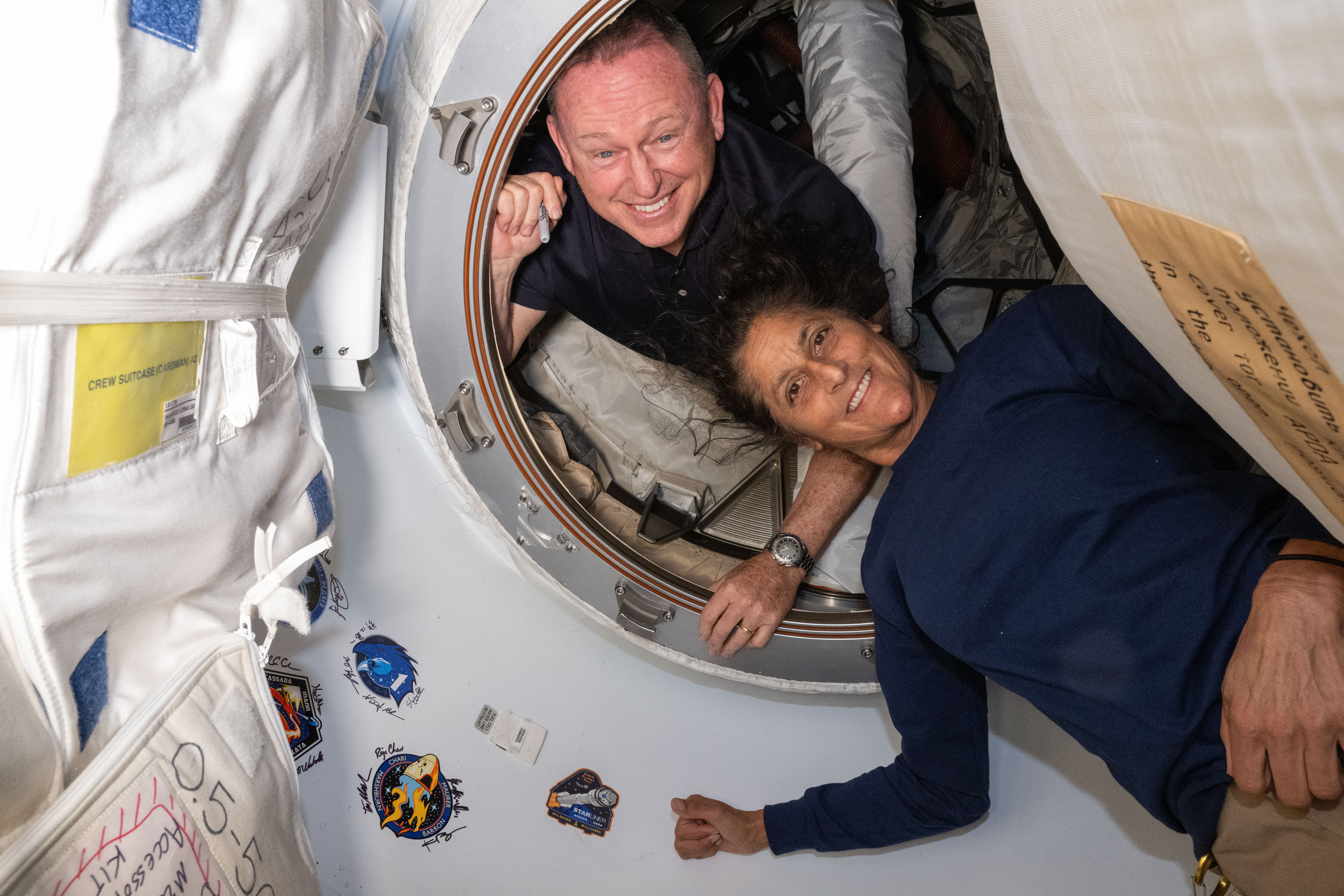 NASA's Boeing Crew Flight Test astronauts (from top) Butch Wilmore and Suni Williams pose for a portrait inside the vestibule between the forward port on the International Space Station's Harmony module and Boeing's Starliner spacecraft.