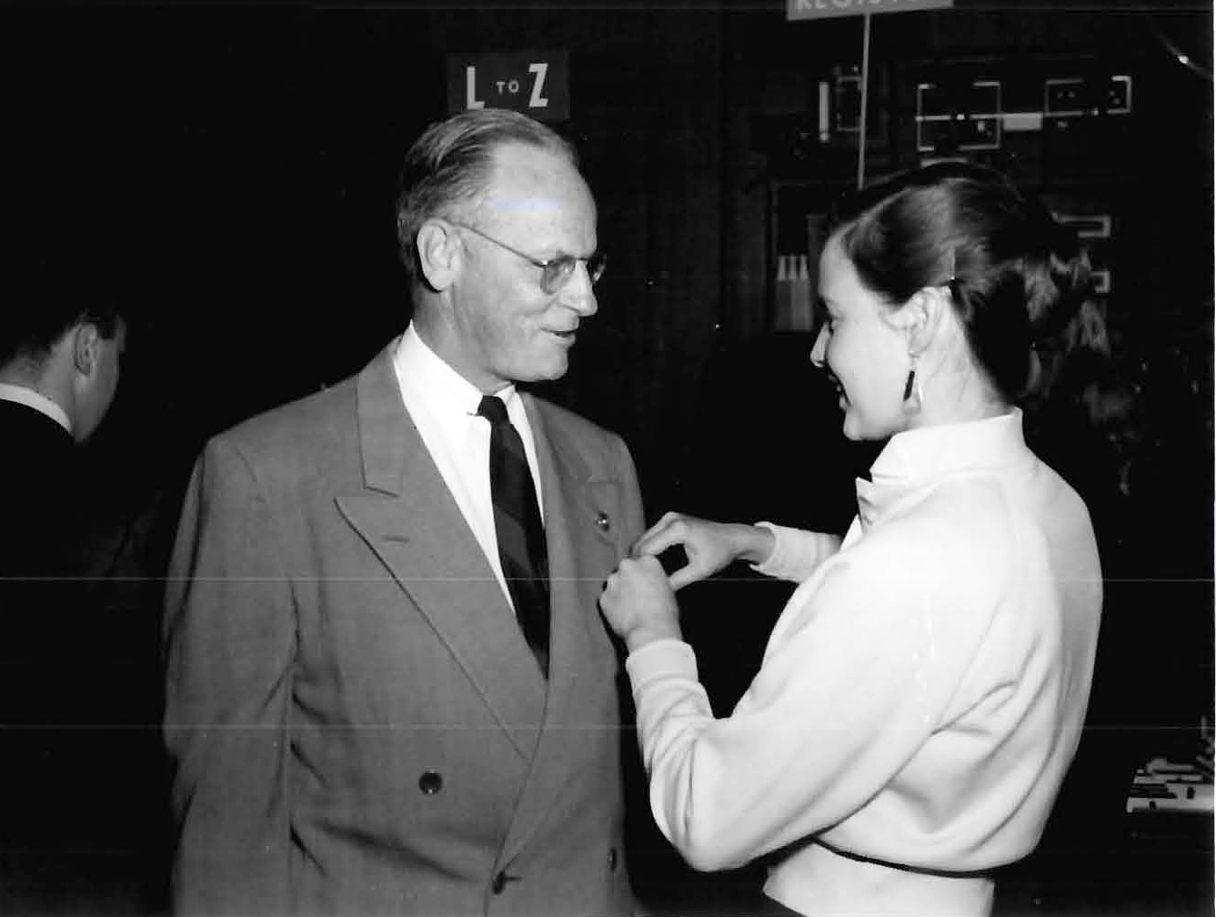 Woman pinning badge on man.