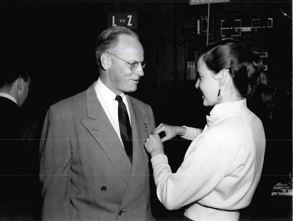 Woman pinning badge on man.