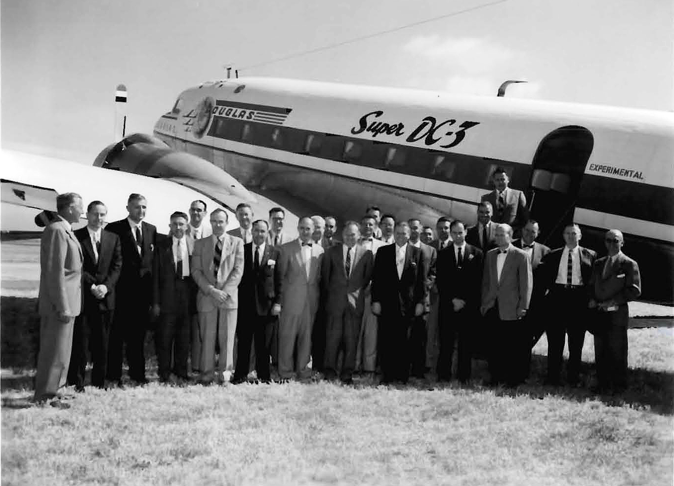 Group standing besides airplane.
