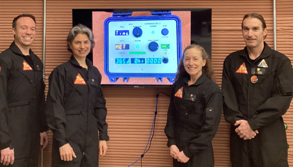 The CHAPEA crew celebrates one year inside the habitat. From left is Medical Officer Nathan Jones, Science Officer Anca Selariu, Commander Kelly Haston, and Flight Engineer Ross Brockwell. Credit: NASA