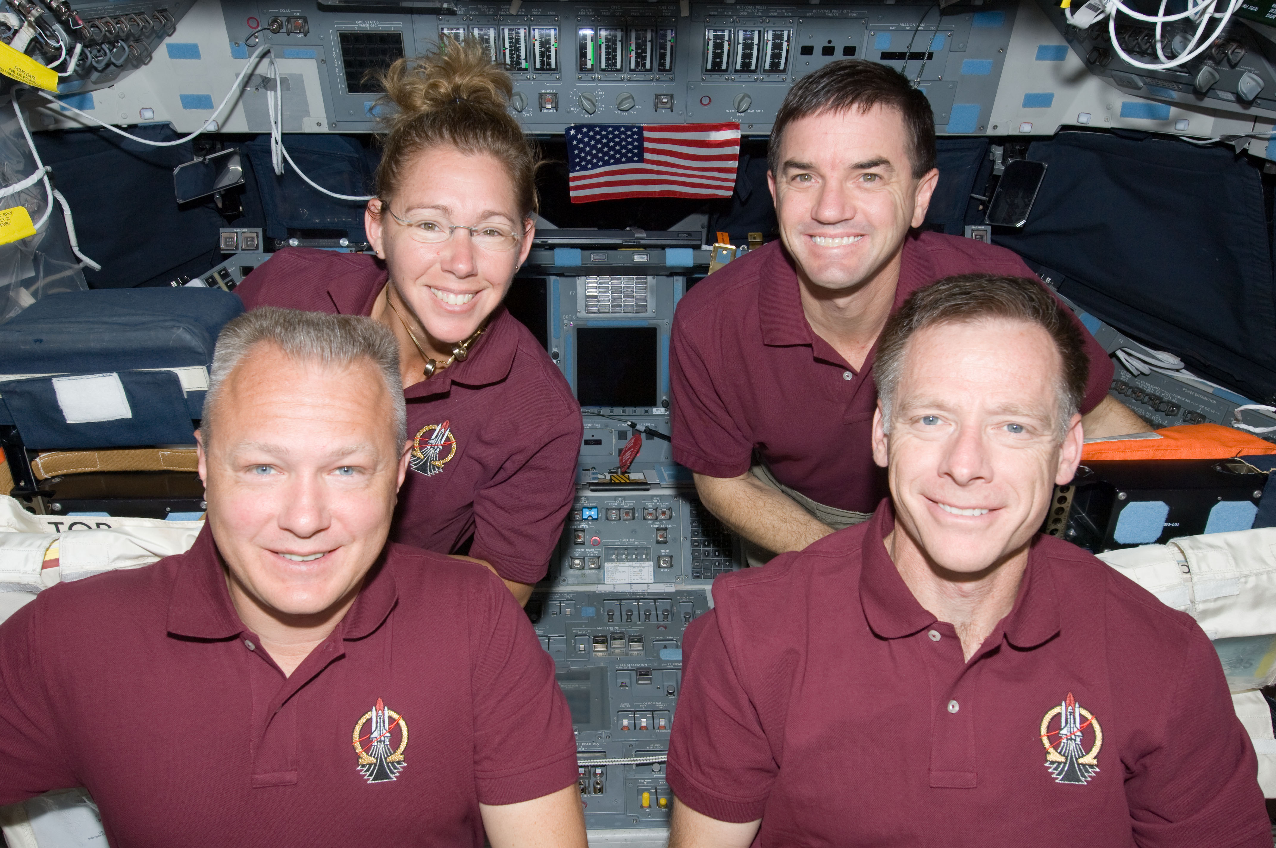The crew of STS-135 pose with the Legacy Flag on the flight deck of Atlantis