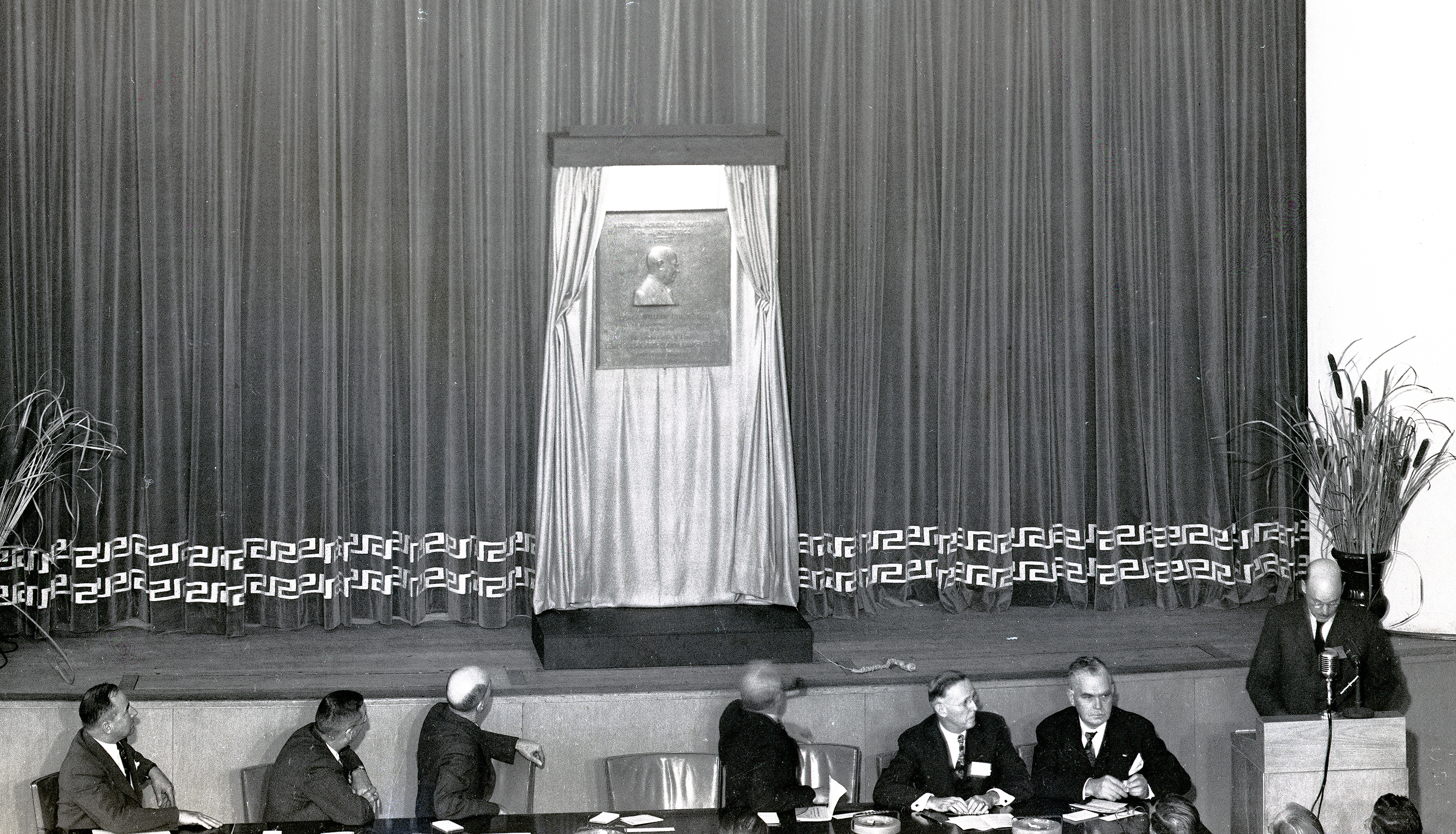 Men seated at table in front of stage.