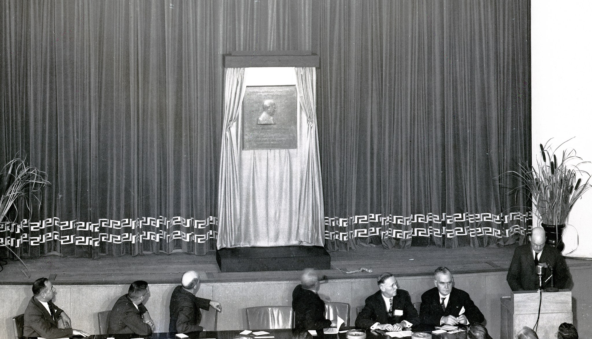 Men seated at table in front of stage.