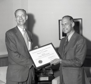 Man presenting award to another.