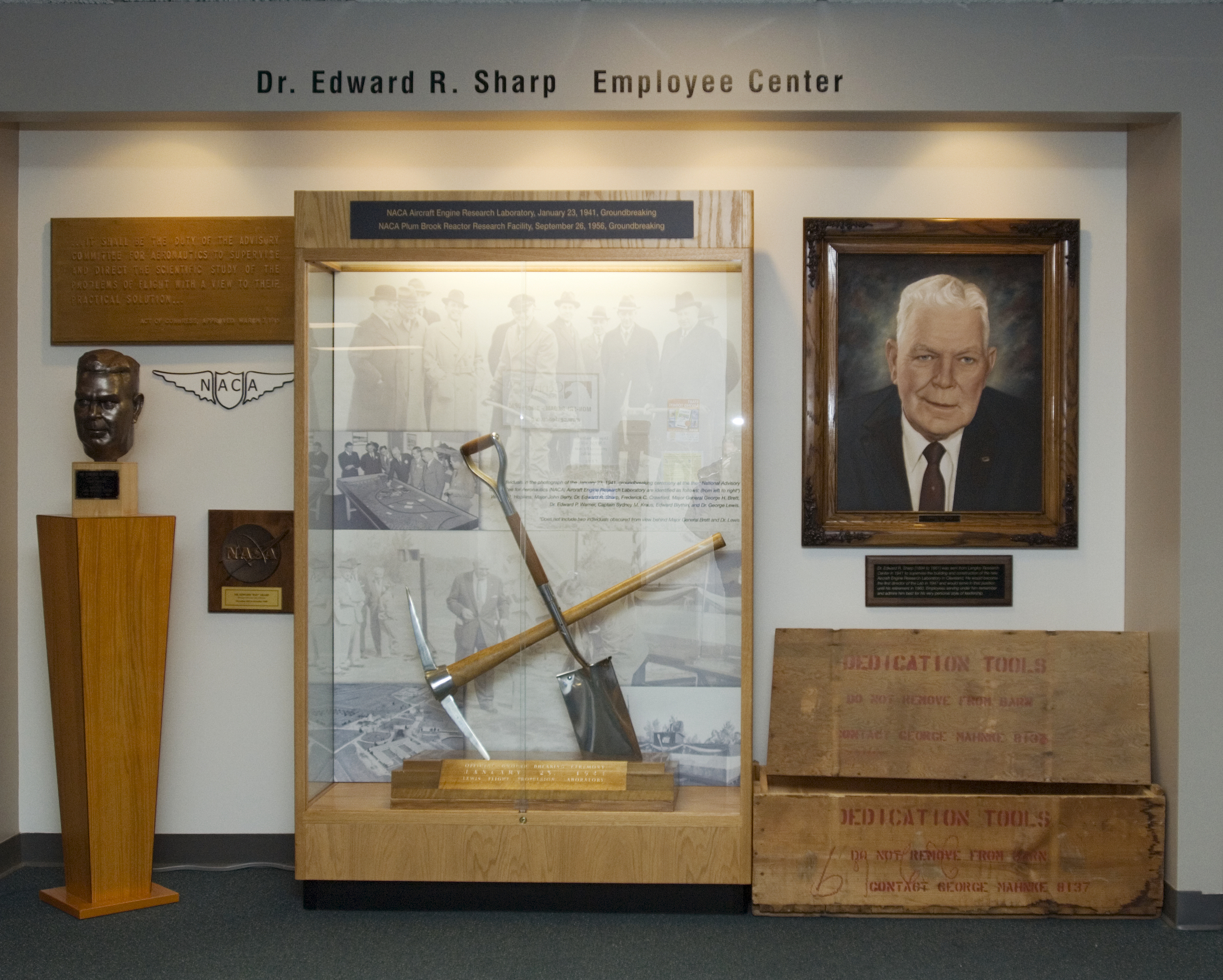 Display case with portrait, pick, and shovel.