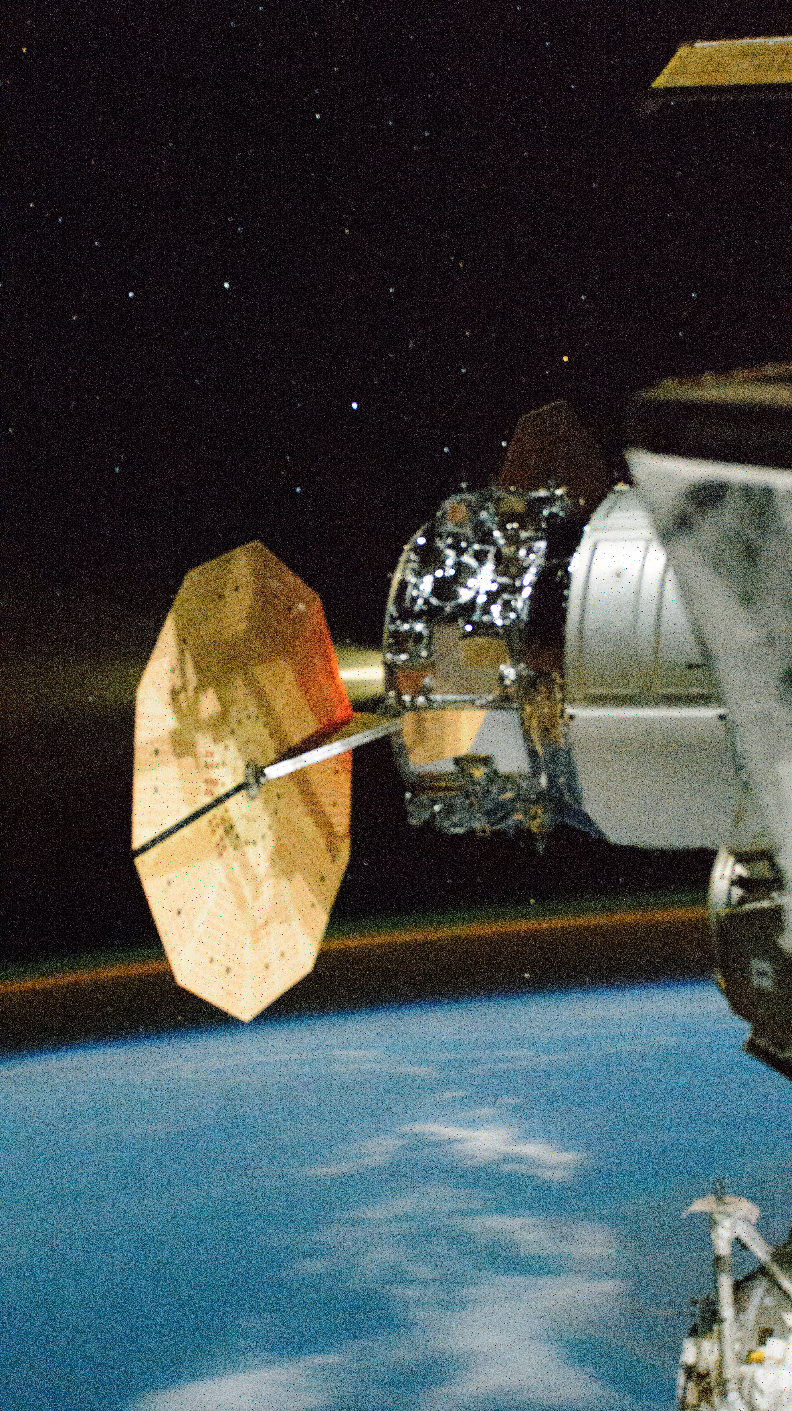 Northrop Grumman's Cygnus space freighter, attached to the Unity module, is pictured firing its single engine boosting the International Space Station's orbital altitude. This long-duration photograph also shows an atmospheric glow hovering above Earth's horizon.