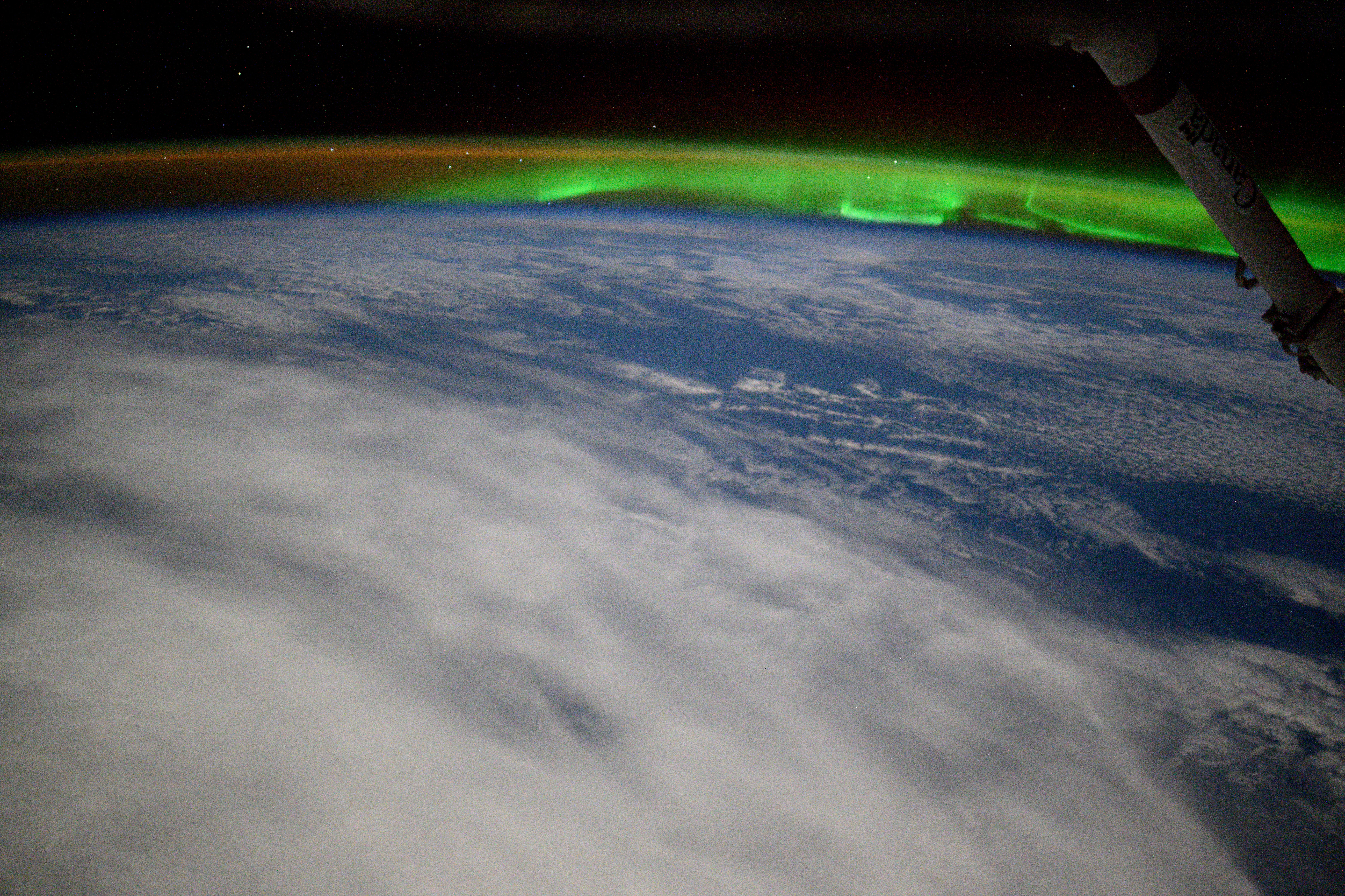 An aurora and an atmospheric glow crown Earth's horizon in this photograph from the International Space Station as it orbited 263 miles above a cloudy Indian Ocean southeast of Africa.