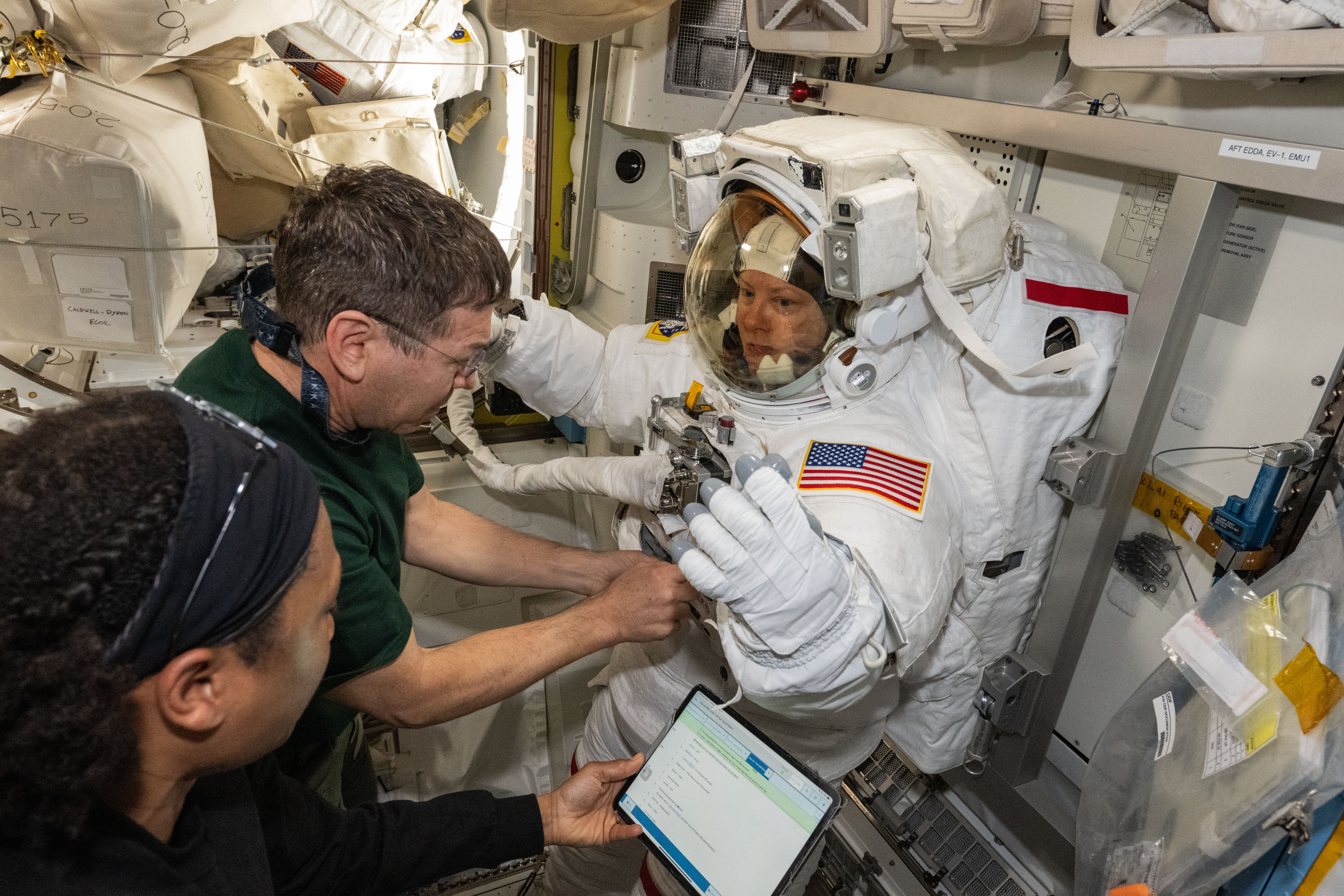 Expedition 71 Flight Engineers (from left) Jeanette Epps and Mike Barratt assist Expedition 71 Flight Engineer Tracy C. Dyson, all three NASA astronauts, during a spacesuit fit check inside the International Space Station's Quest airlock.