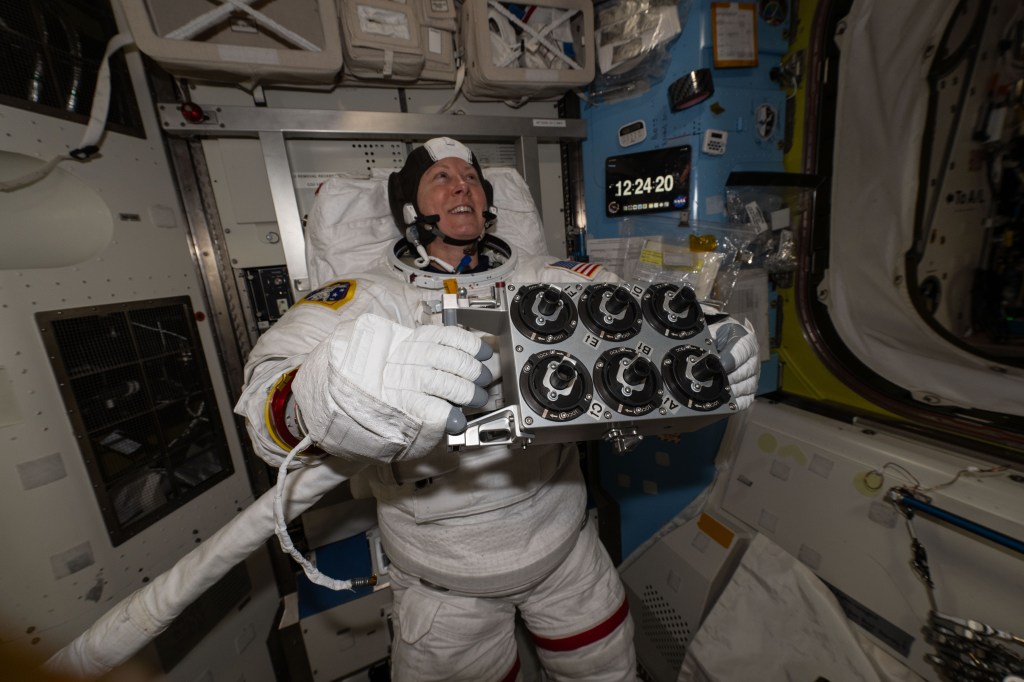 Expedition 71 Flight Engineer and NASA astronaut Tracy C. Dyson is pictured during a spacesuit fit check and holding spacewalk hardware inside the International Space Station's Quest airlock.