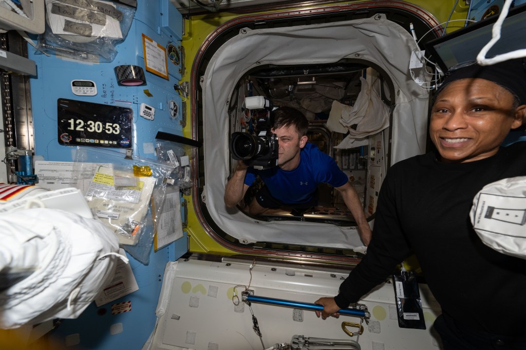 Expedition 71 Flight Engineer Matthew Dominick photographs activities in the International Space Station's Quest airlock as Expedition 71 Flight Engineer Jeanette Epps looks on. Dominick and Epps are both NASA astronauts on their first long-term space mission.