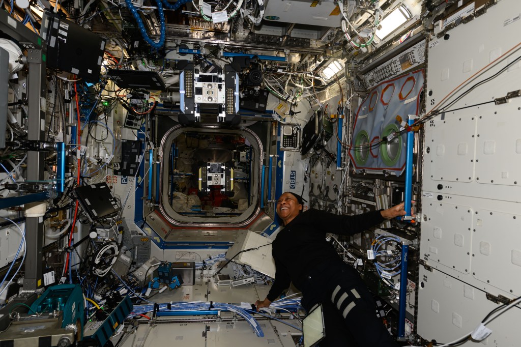 Expedition 71 Flight Engineer and NASA astronaut Jeanette Epps observes an Astrobee robotic free flyer during an operations test inside the International Space Station's Kibo laboratory module.