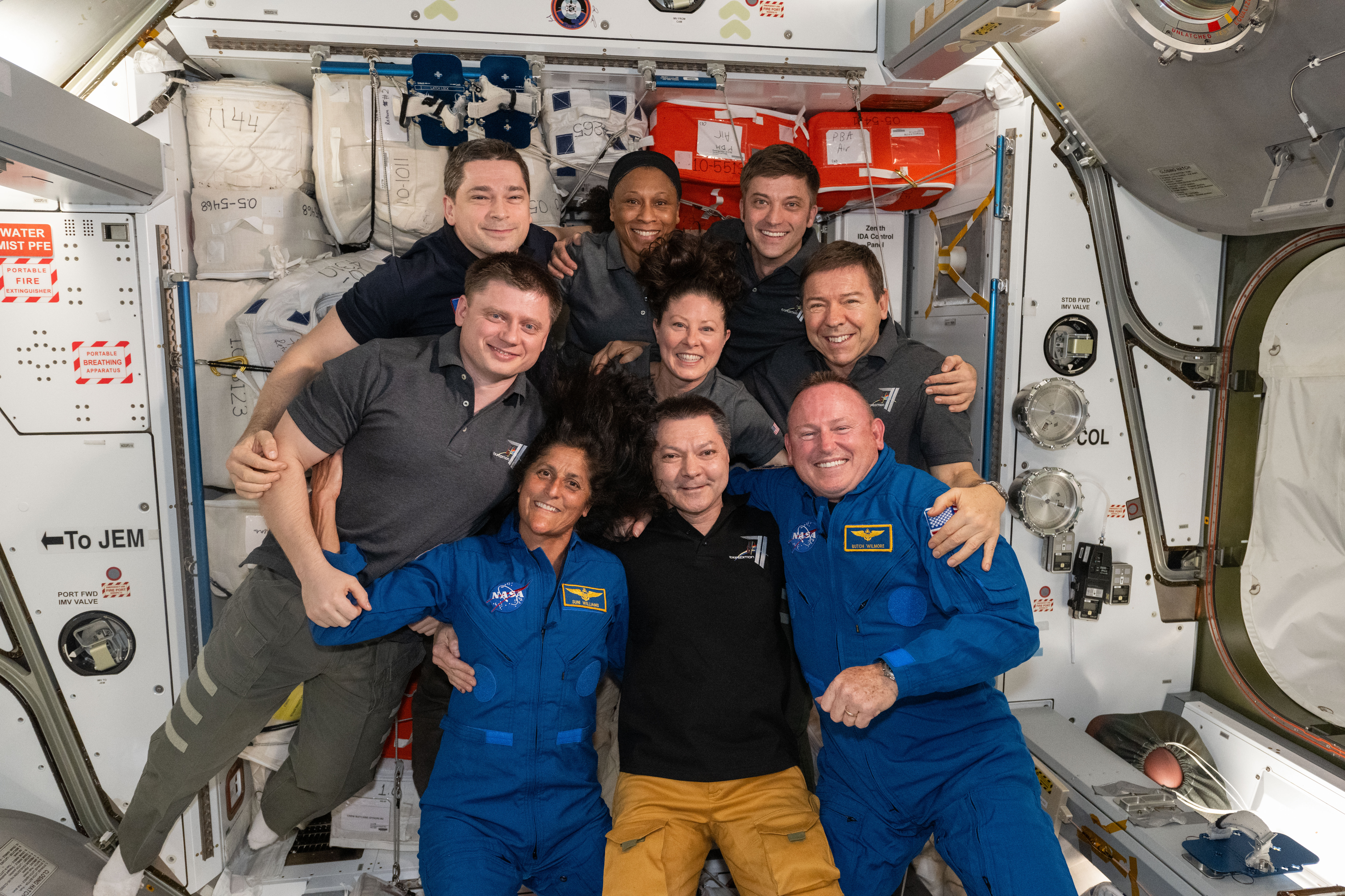 The seven Expedition 71 crew members gather with the two Crew Flight Test members for a team portrait aboard the space station. In the front from left are, Suni Williams, Oleg Kononenko, and Butch Wilmore. Second row from left are, Alexander Grebenkin, Tracy C. Dyson, and Mike Barratt. In the back are, Nikolai Chub, Jeanette Epps, and Matthew Dominick.