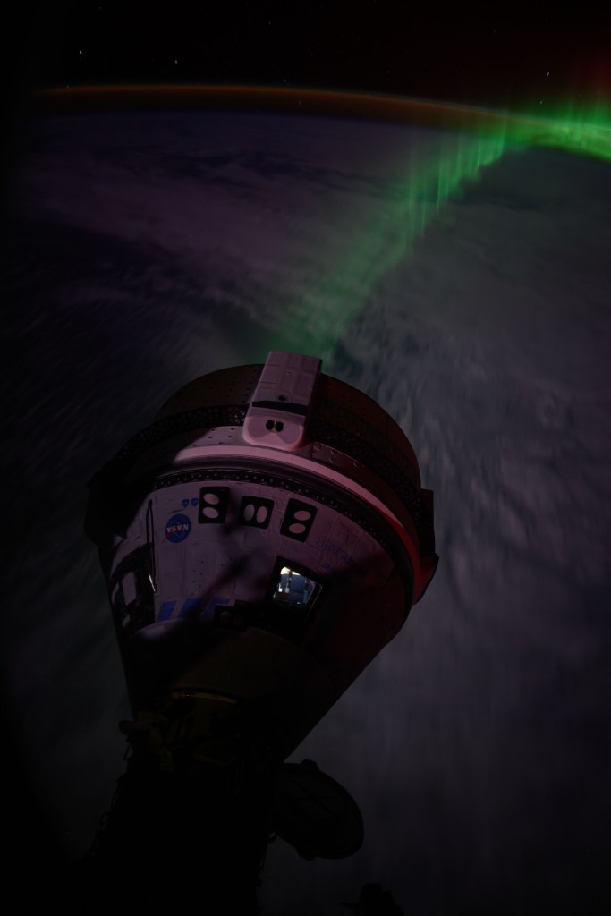 An aurora streams below Boeing's Starliner spacecraft docked to the forward port on the Harmony module as the International Space Station soared 266 miles above the Indian Ocean southwest of Australia.