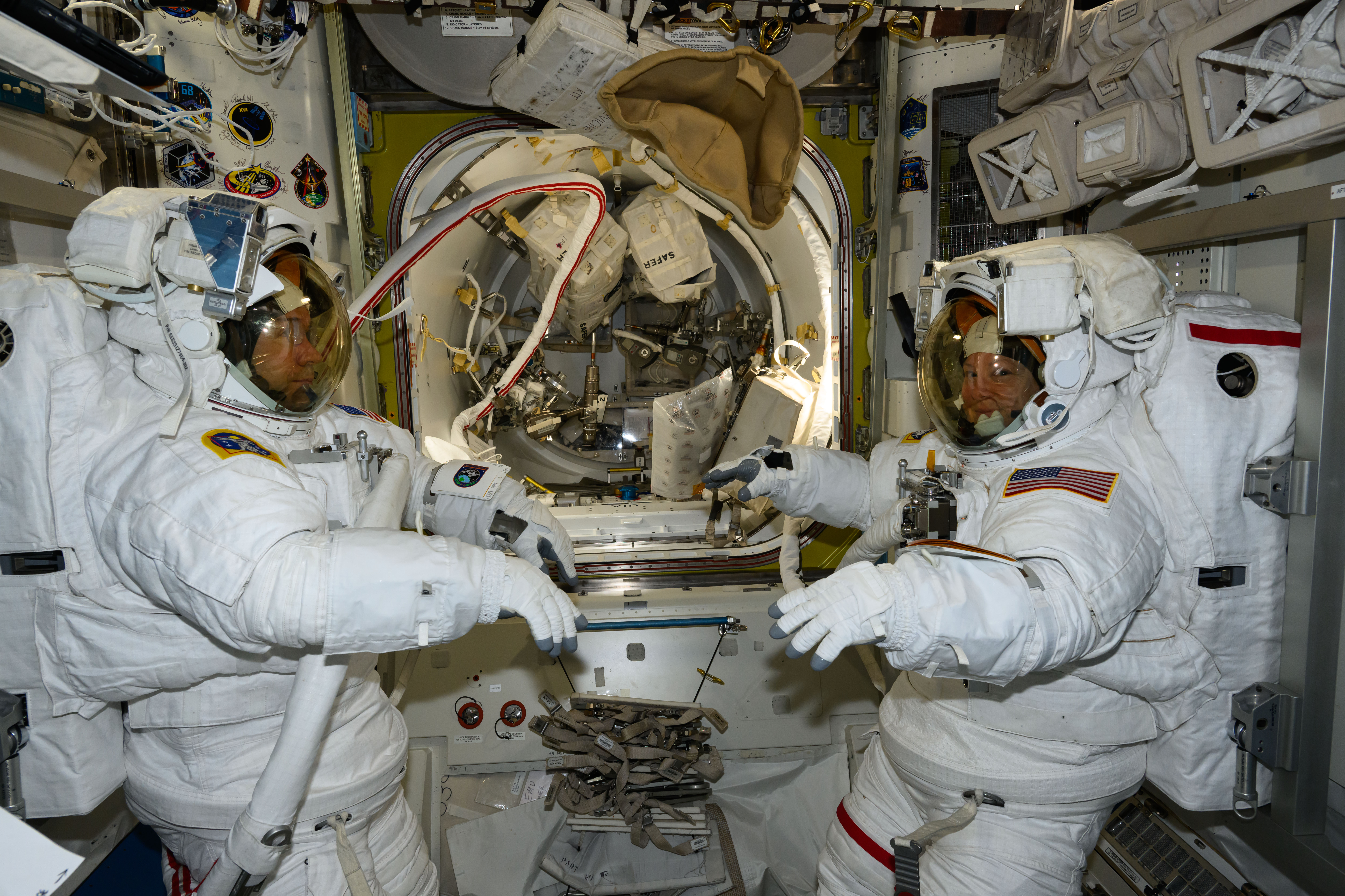NASA astronauts (from left) Mike Barratt and Tracy C. Dyson, both Expedition 71 Flight Engineers, are pictured in the Quest airlock prior to the start of a science and maintenance spacewalk that ended early after Dyson's suit experienced a water leak in the service and cooling umbilical unit.