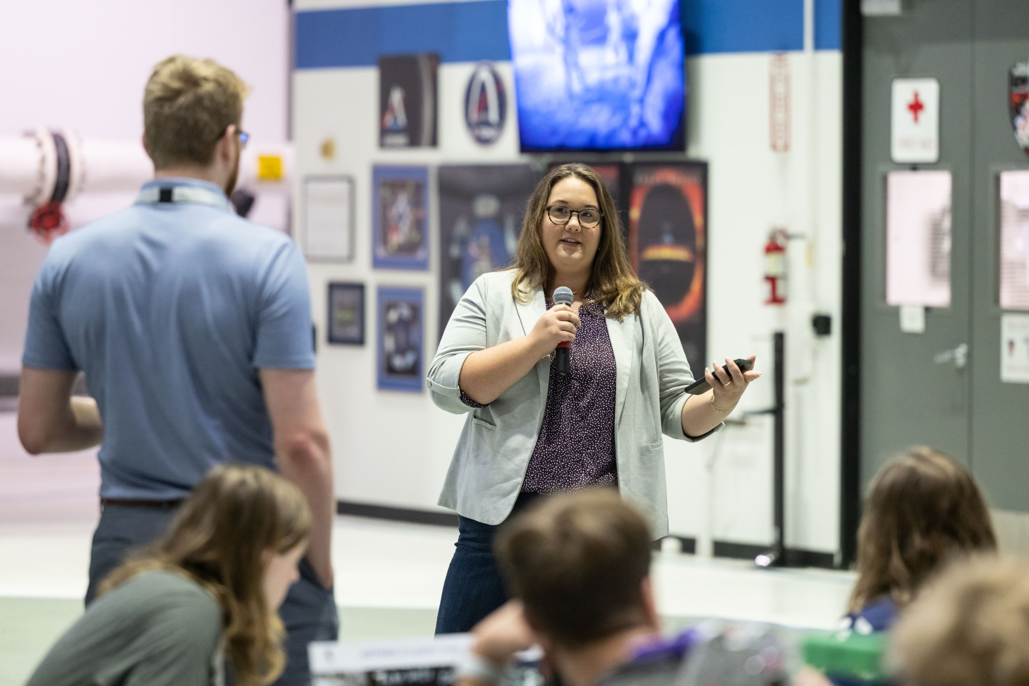 A woman talks with a microphone in front of students at NASA's Neutral Buoyancy Laboratory in Houston, Texas.