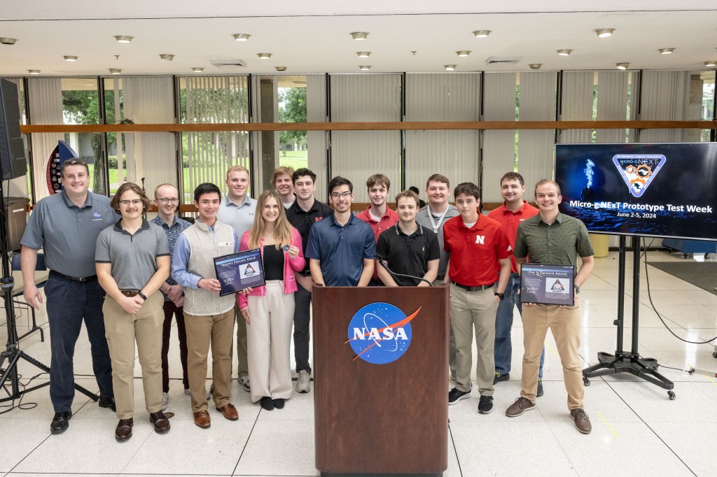 Students, mentors, and NASA personnel pose with two awards at Johnson Space Center in Houston.