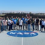 A group of people from the Intelligent Robotics Group at NASA Ames Research Center pose around a NASA logo.