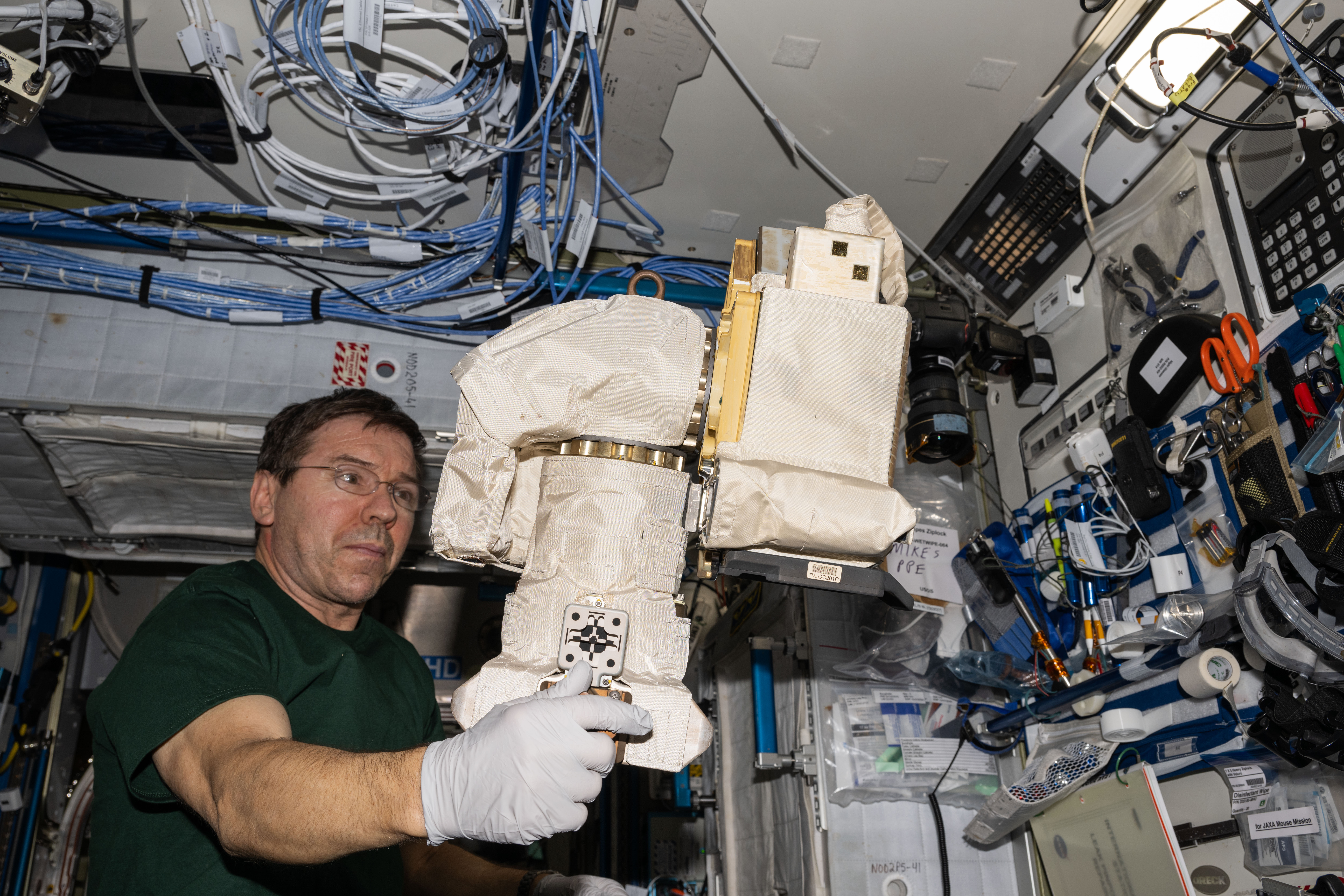 NASA astronaut and Expedition 71 Flight Engineer Mike Barratt works on spacewalking hardware aboard the International Space Station's Unity module.