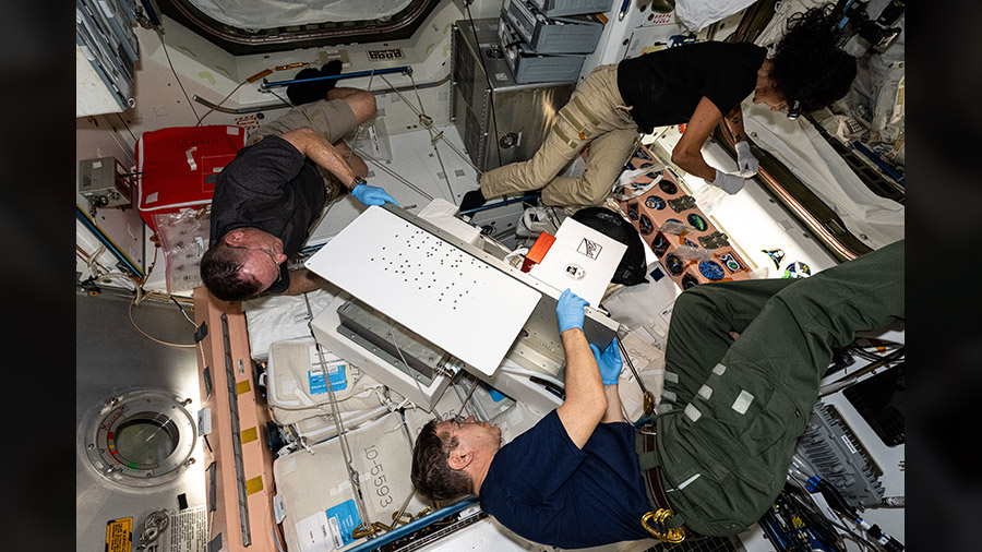 Clockwise from bottom, NASA astronauts Mike Barratt, Butch Wilmore, and Suni Williams work on science maintenance inside the International Space Station's Unity module.