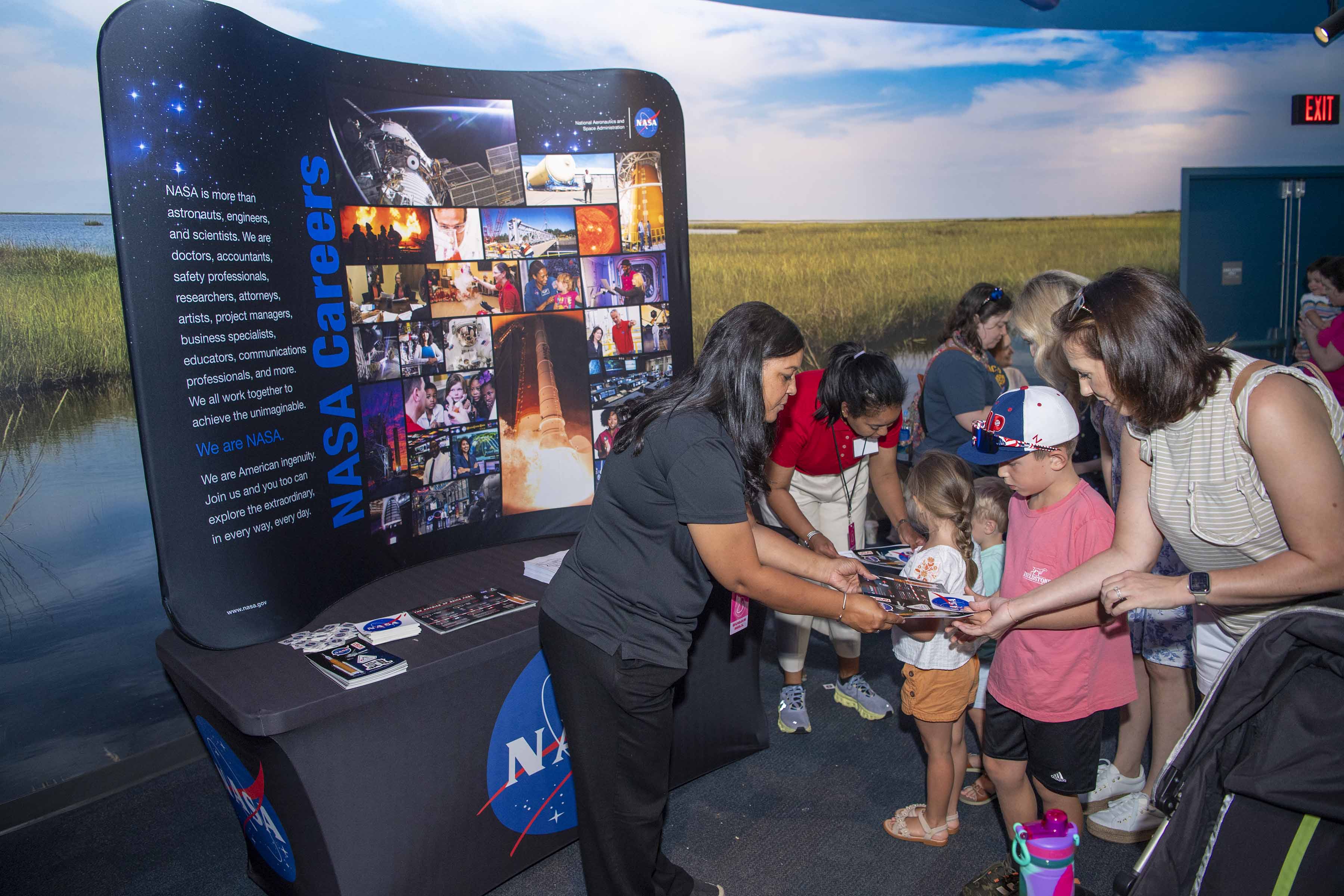 NASA representatives distribute memorabilia to young visitors at the Audubon Aquarium during Essence Fest