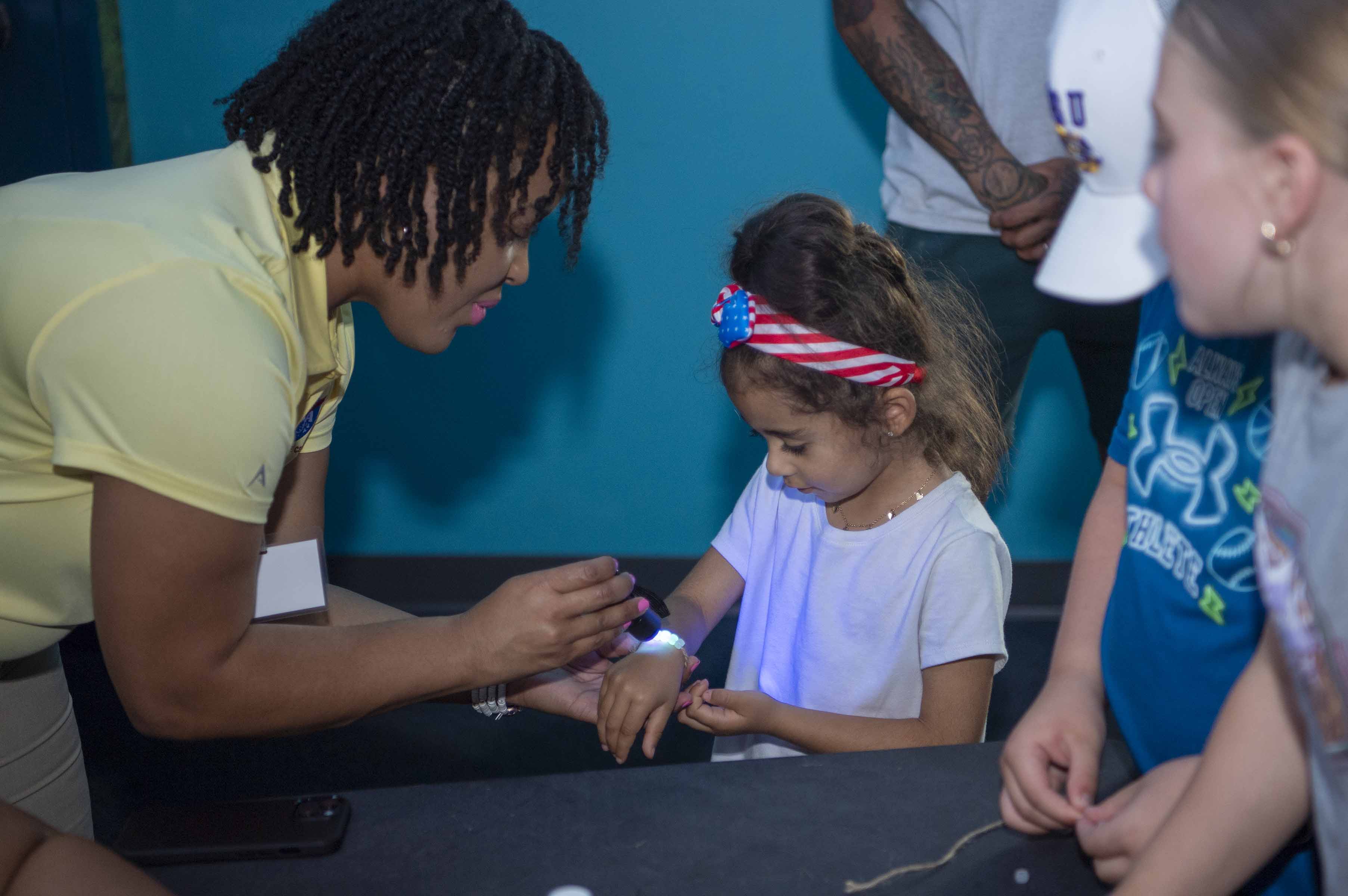 NASA Public Affairs Specialist Samone Wilson uses solar beads to teach a young visitor at the Audubon Aquarium about skin protection
