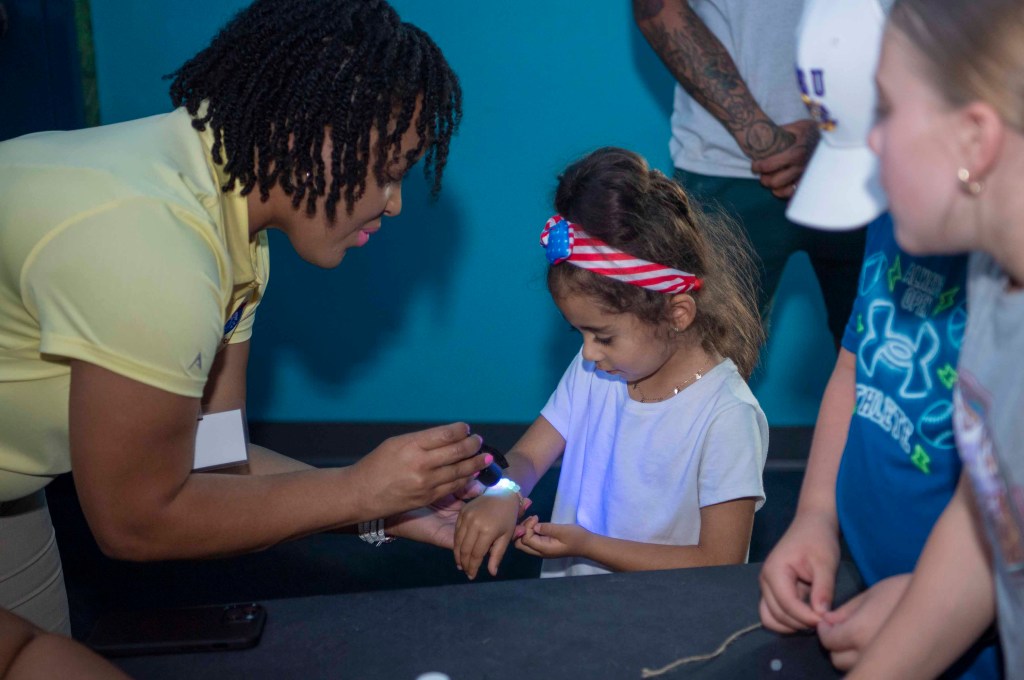 NASA Public Affairs Specialist Samone Wilson uses solar beads to teach a young visitor at the Audubon Aquarium about skin protection