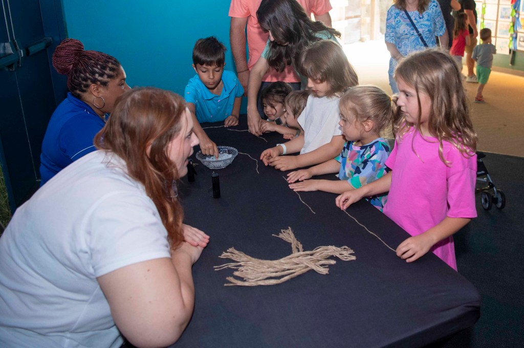 NASA representatives welcome a group of young visitors at Audubon Aquarium