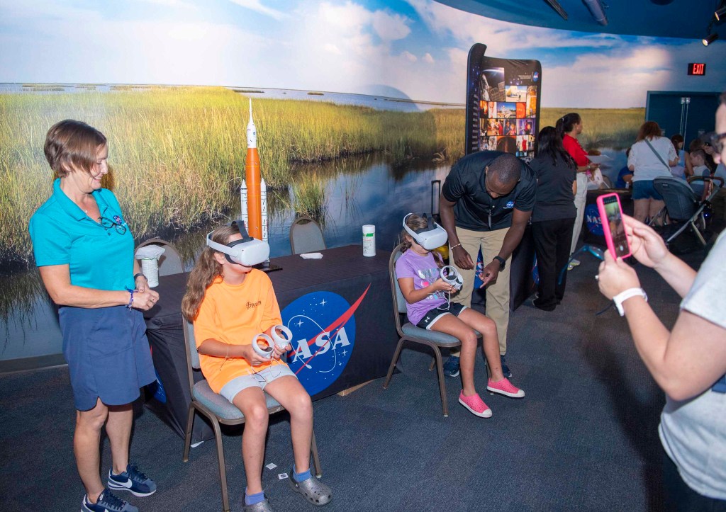 Two young visitors at the Audubon Aquarium get a virtual reality experience while NASA representatives standby to assist