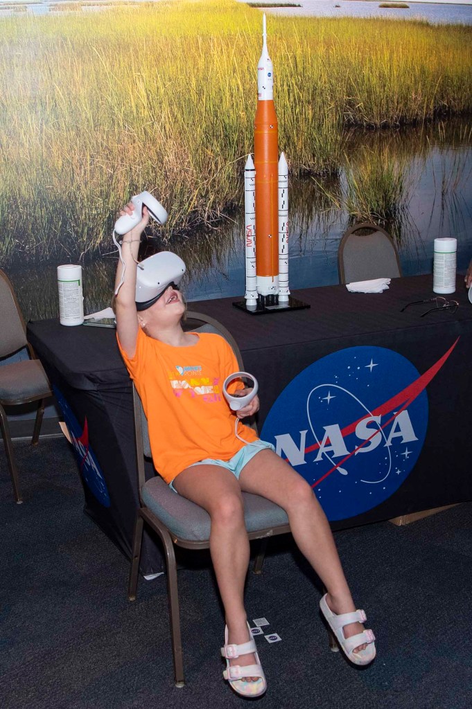a young visitor uses virtual reality eyewear while sitting at the NASA booth at Audubon Aquarium