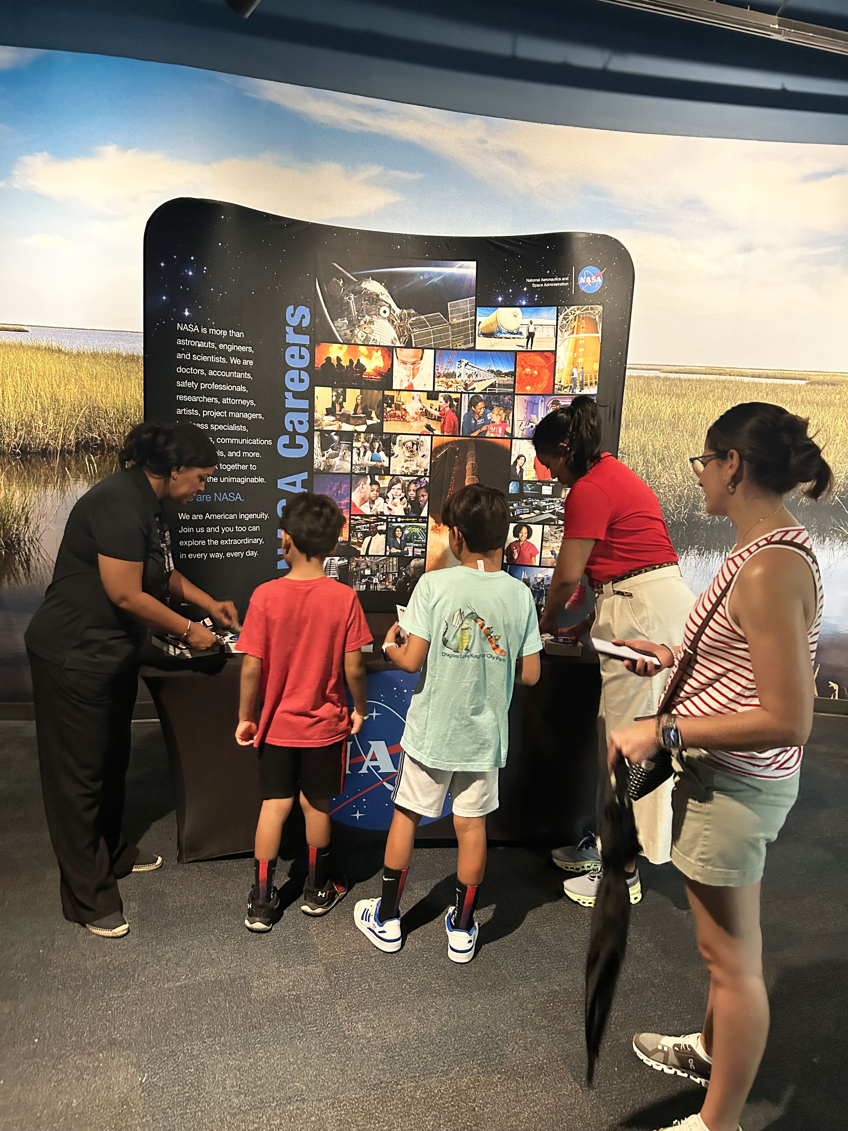 Two NASA representatives engage with young visitors who stopped at the NASA booth at Essesnce Fest
