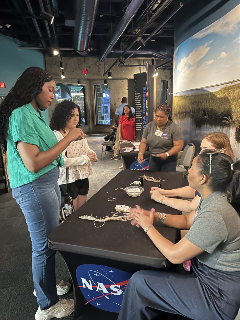two visitors perform activity while interacting at the NASA booth at Essence Fest