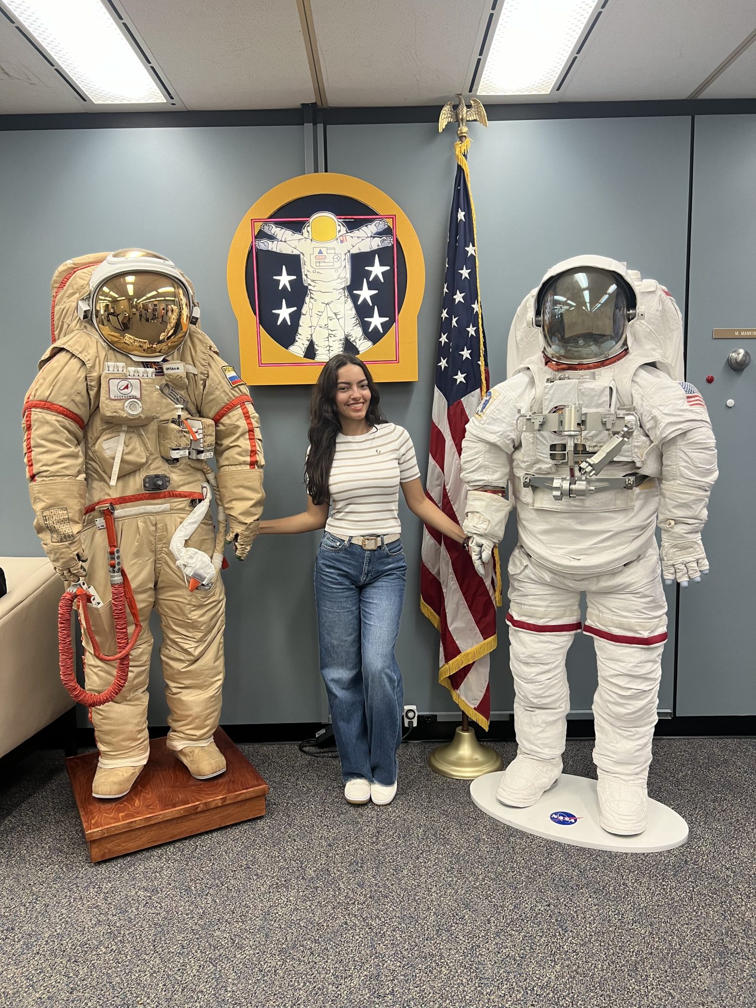 A young woman stands between two spacesuit displays.