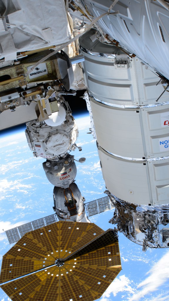 Pictured in the foreground, is Northrop Grumman's Cygnus space freighter, berthed to the International Space Station's Unity module, and one of two of its cymbal-shaped UltraFlex solar arrays. In the rear, is the Soyuz MS-25 crew ship docked to the Prichal docking module. The orbital outpost was soaring 263 miles above the Pacific Ocean south of Midway Atoll.