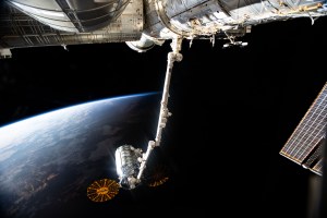 Northrop Grumman's Cygnus space freighter is pictured attached to the Canadarm2 robotic arm ahead of its release from the International Space Station's Unity module. The orbiting lab and Cygnus were soaring into orbital daytime as this photo was taken.