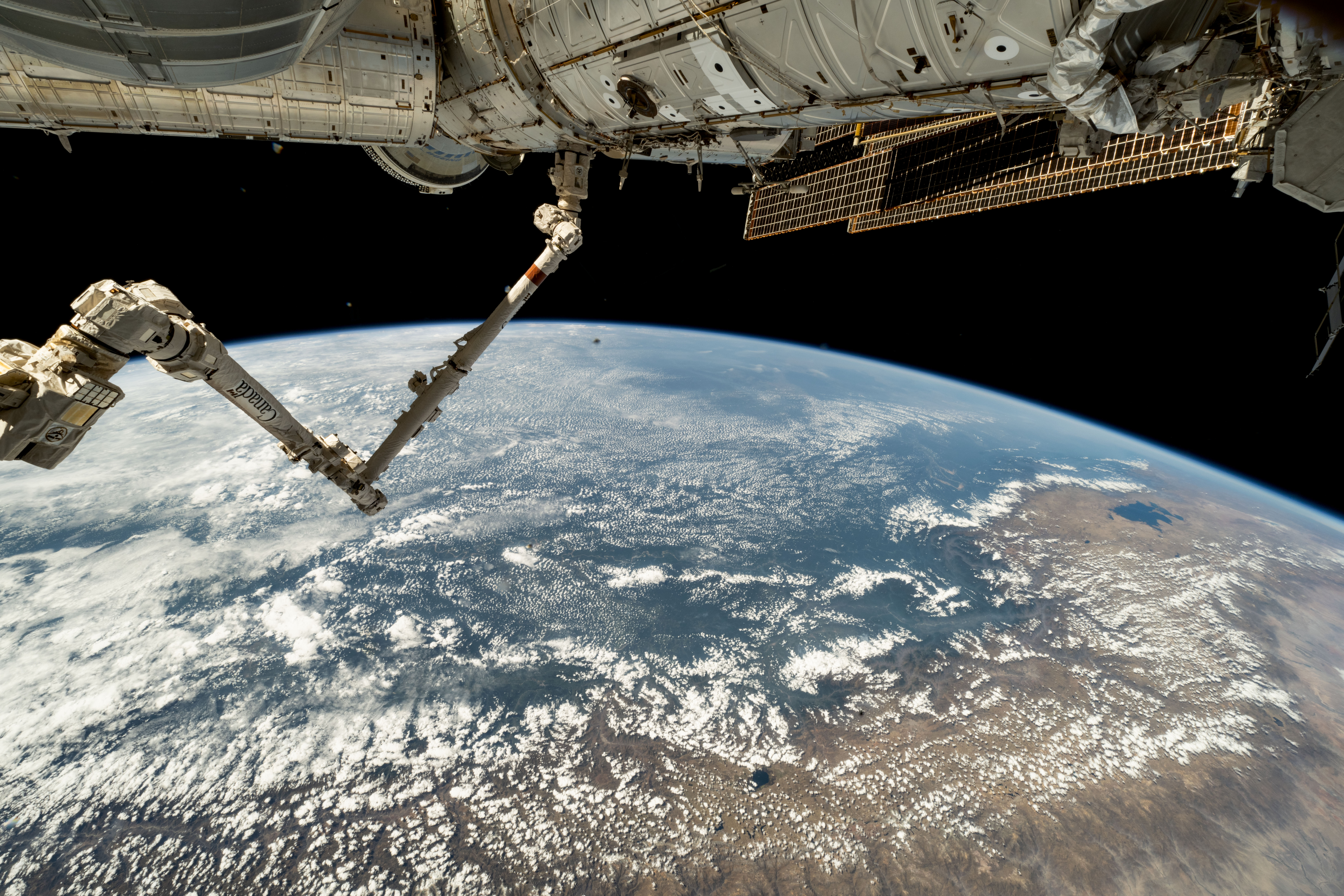 The 57.7-foot-long Canadarm2 robotic arm extends from the International Space Station's Harmony module as the orbital outpost soared 261 miles above the coast of Peru. Partially obscured in the top background, is the Boeing Starliner spacecraft docked to Harmony's forward port.