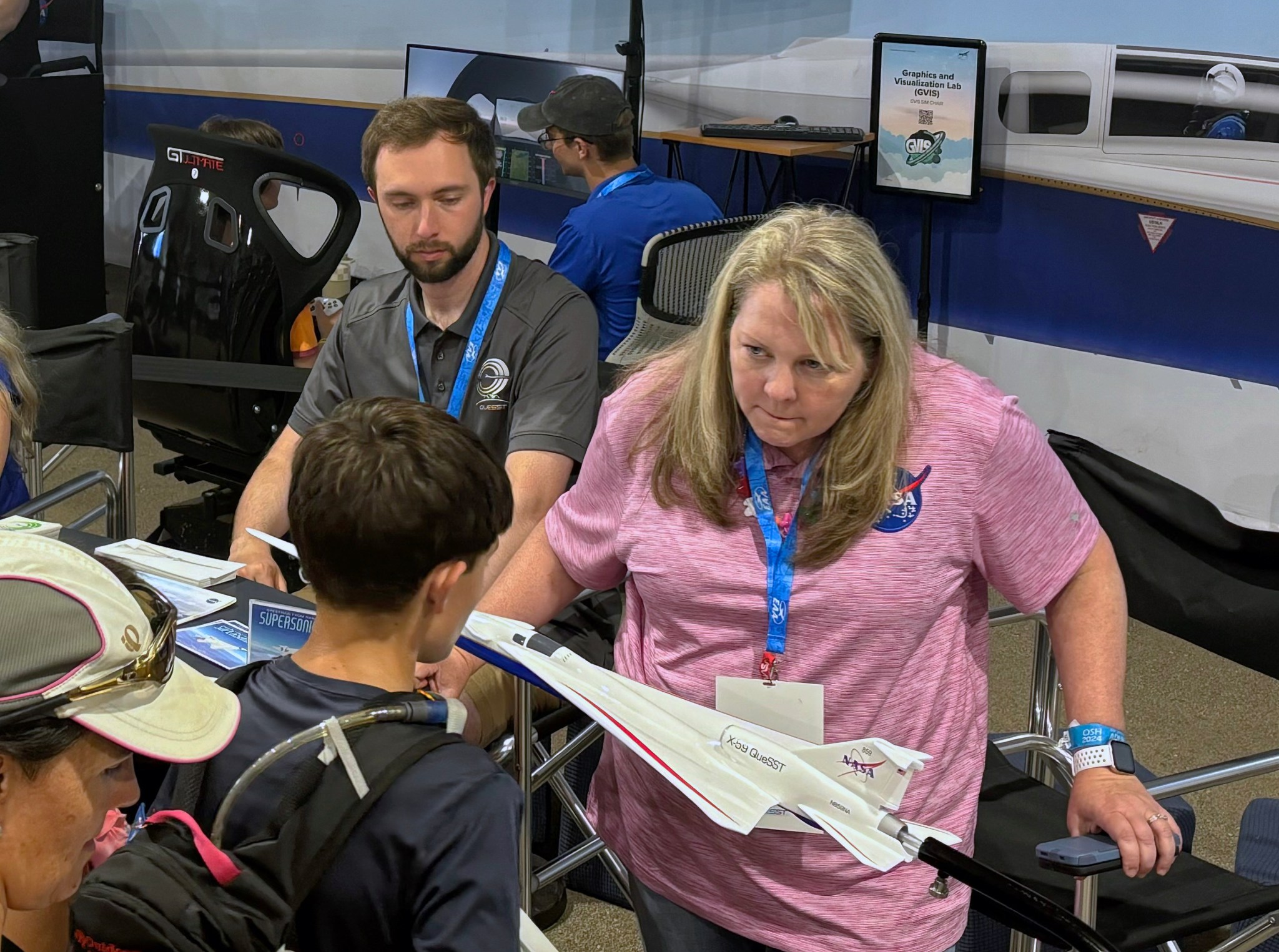 A group of people stand around a small model of an airplane.