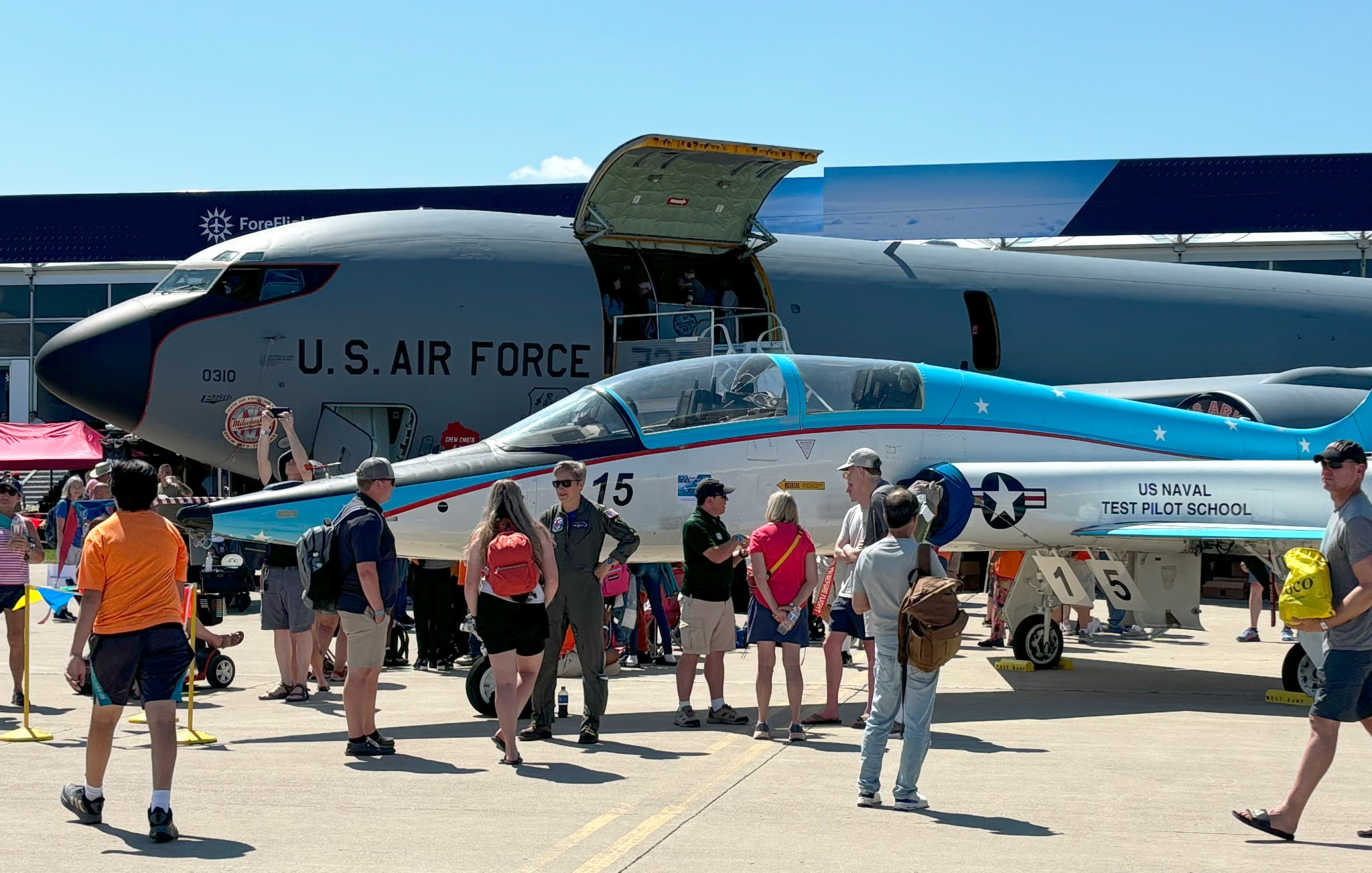 Two jet aircraft on display have a group of people walking around them.