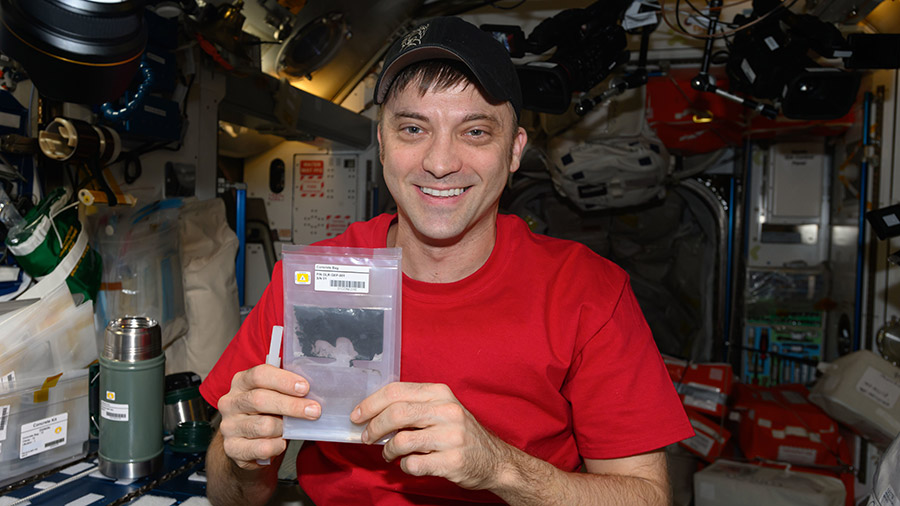 Astronaut Matthew Dominick displays a bag containing simulated lunar cement to explore how cement materials could be used to build infrastructure on the lunar surface.