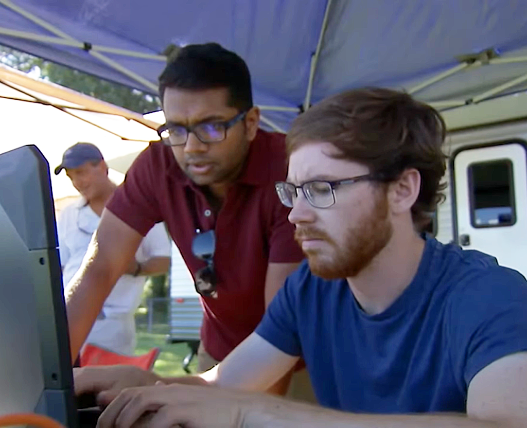 Two people work at a laptop.