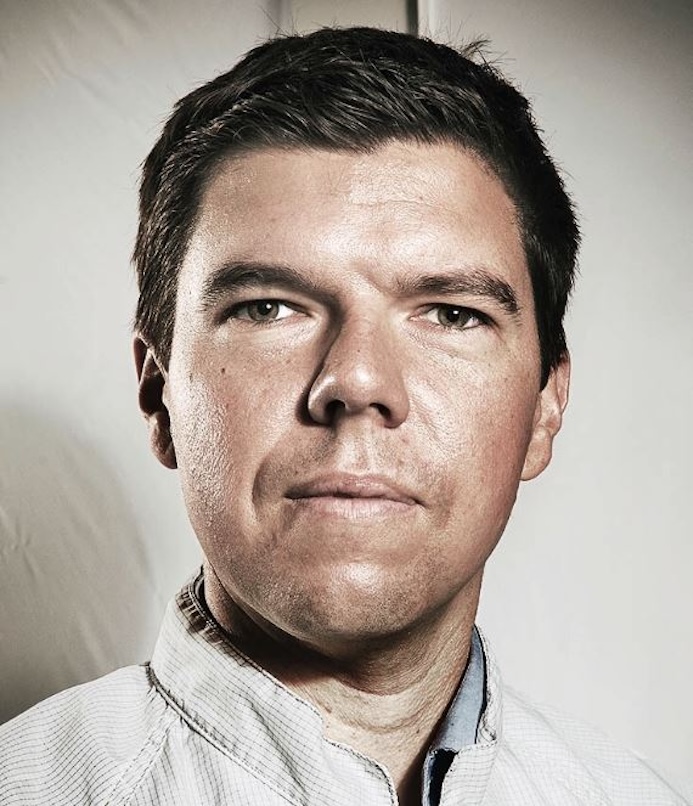 Headshot of Ryan McClelland. He is wearing a white button down shirt and staring directly at the camera.