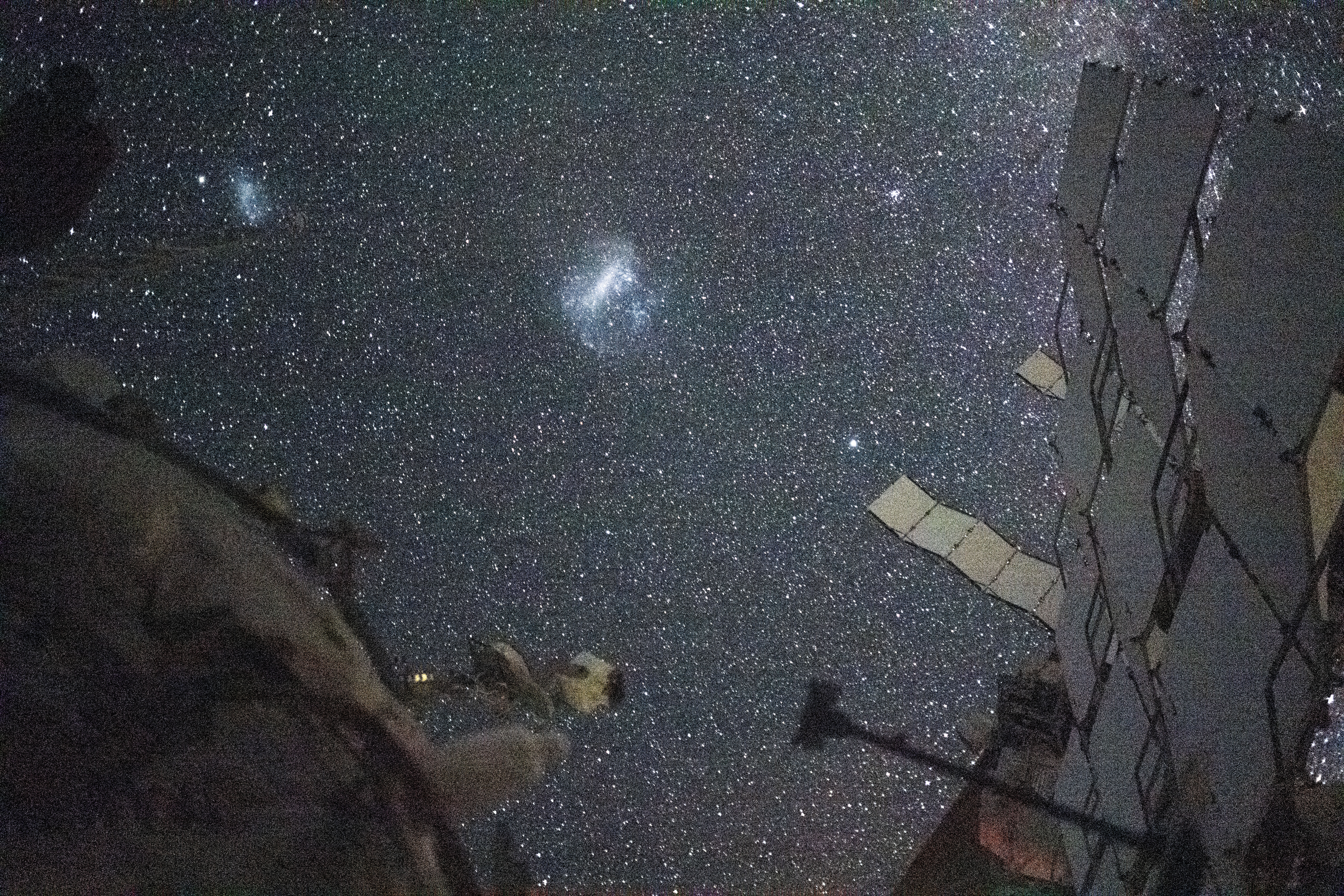 The Large Magellanic Cloud (center) and the Small Magellanic Cloud (upper left), dwarf galaxies in close proximity with the Milky Way galaxy, are pictured from the International Space Station. NASA astronaut and Expedition 71 Flight Engineer Matthew Dominick took this long-duration photograph with a station camera increasing its sensitivity to account for low light conditions.