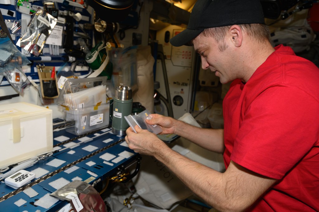 NASA astronaut and Expedition 71 Flight Engineer Matthew Dominick mixes bags containing simulated lunar soil and other materials with a liquid solution before inserting them inside a thermos can for overnight incubation. He was exploring how microgravity affects the production of cement materials that could be used to build infrastructure on the lunar surface.