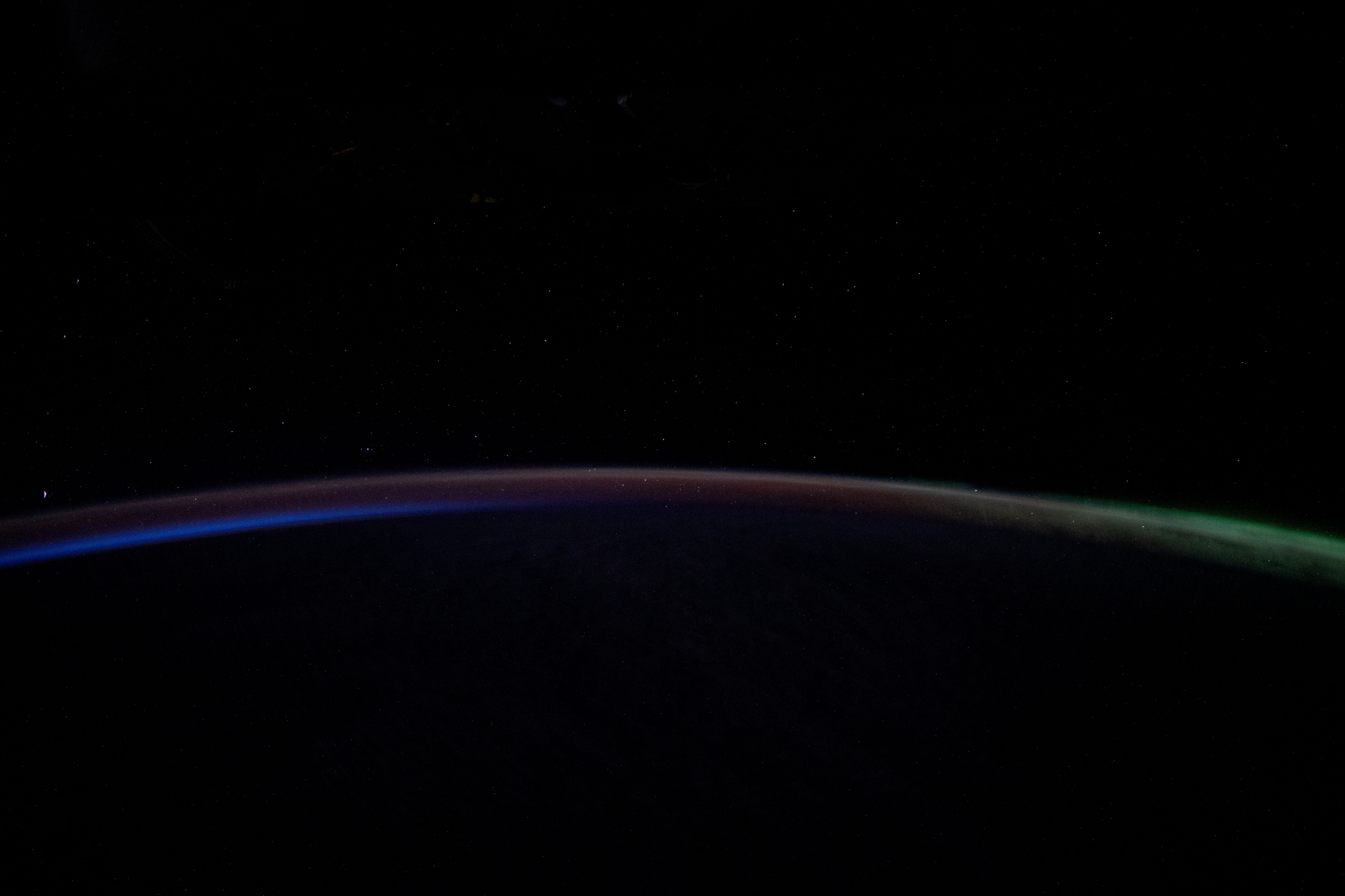 A dim Aurora Australis (at right) blankets the Earth's horizon and fades into a dawning orbital sunrise in this photograph from the International Space Station as it orbited 263 miles above the Pacific Ocean southeast of New Zealand.