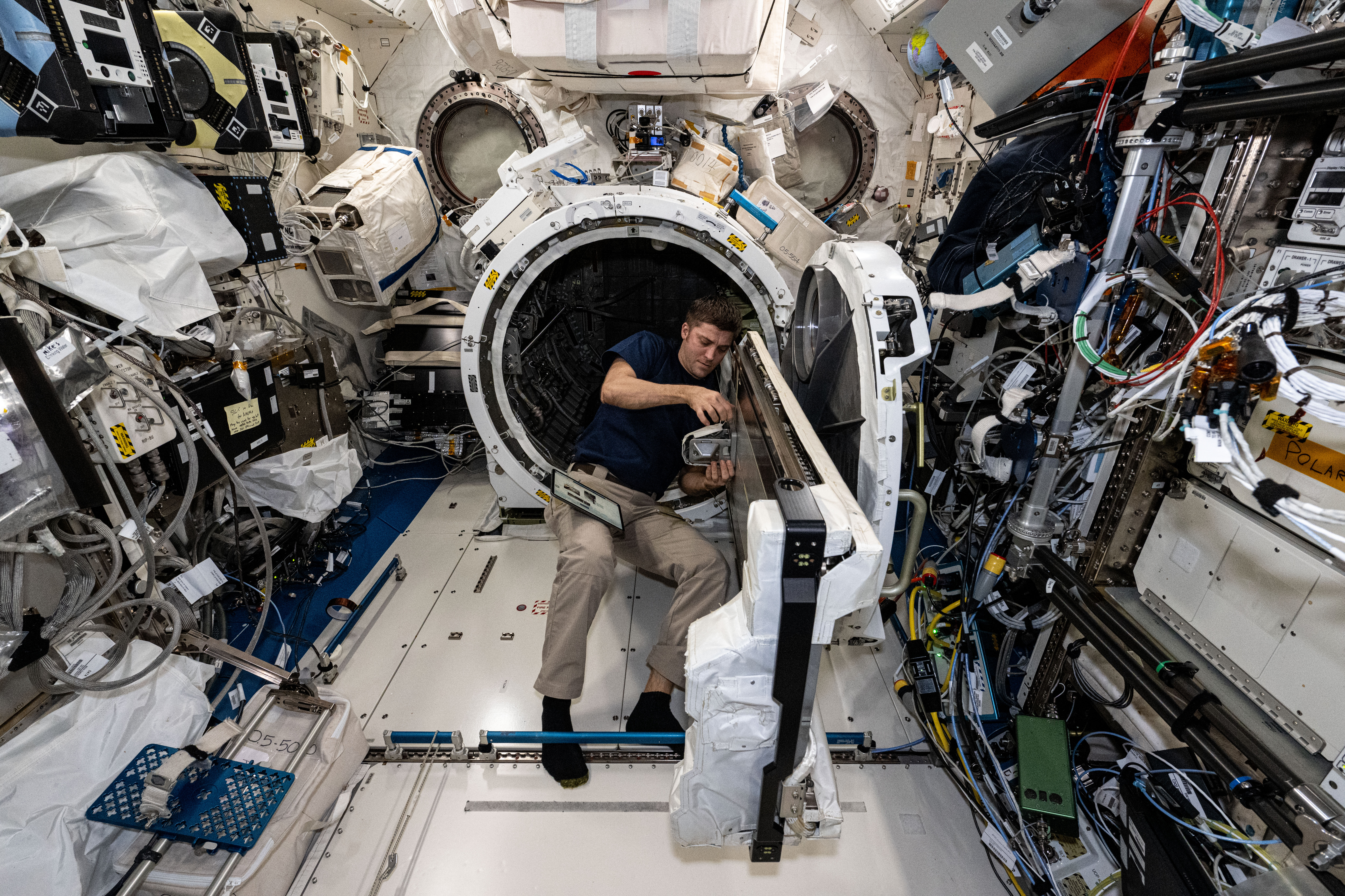 NASA astronaut and Expedition 71 Flight Engineer Matthew Dominick checks CubeSat configurations packed inside launch cases installed in the Kibo laboratory module's Small Satellite Orbital Deployer.