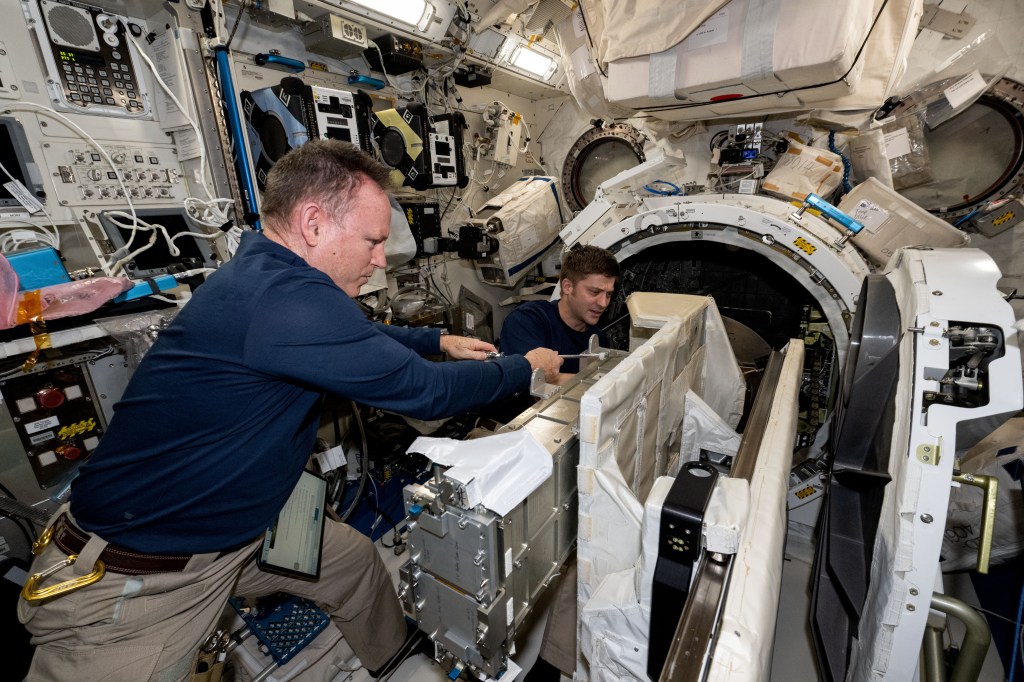 NASA astronauts (from left) Butch Wilmore, Commander for Boeing's Crew Flight Test, and Matthew Dominick, Expedition 71 Flight Engineer, check CubeSat configurations inside the Small Satellite Orbital Deployer aboard the International Space Station's Kibo laboratory module.